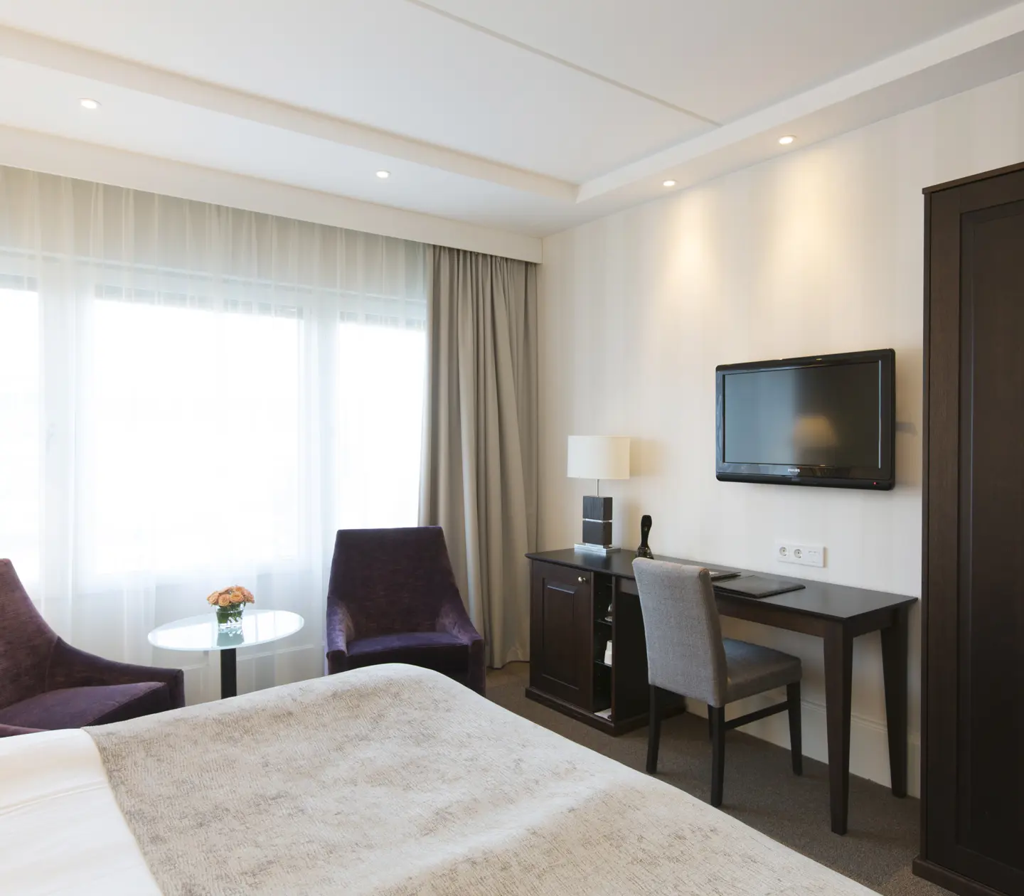 Ljust hotellrum med skrivbord, fåtöljer och garderob