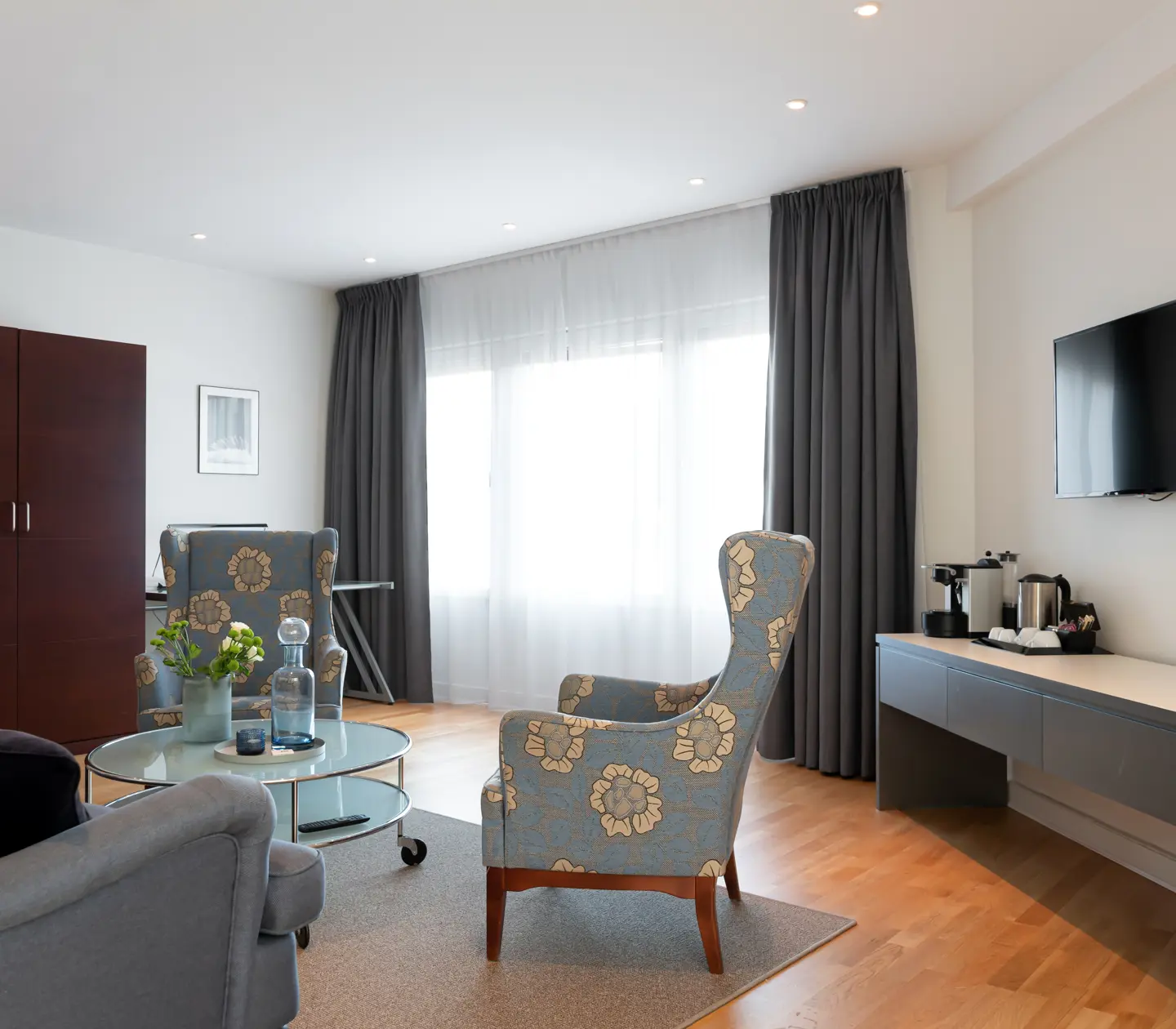 Ljus hotellsvit med soffgrupp, tv och garderob