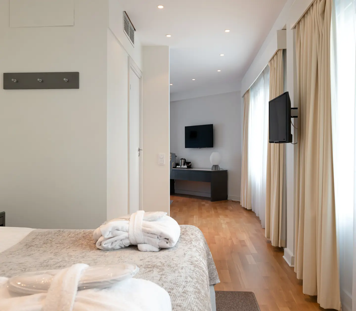 Ljus hotellsvit med säng, tv och fönster