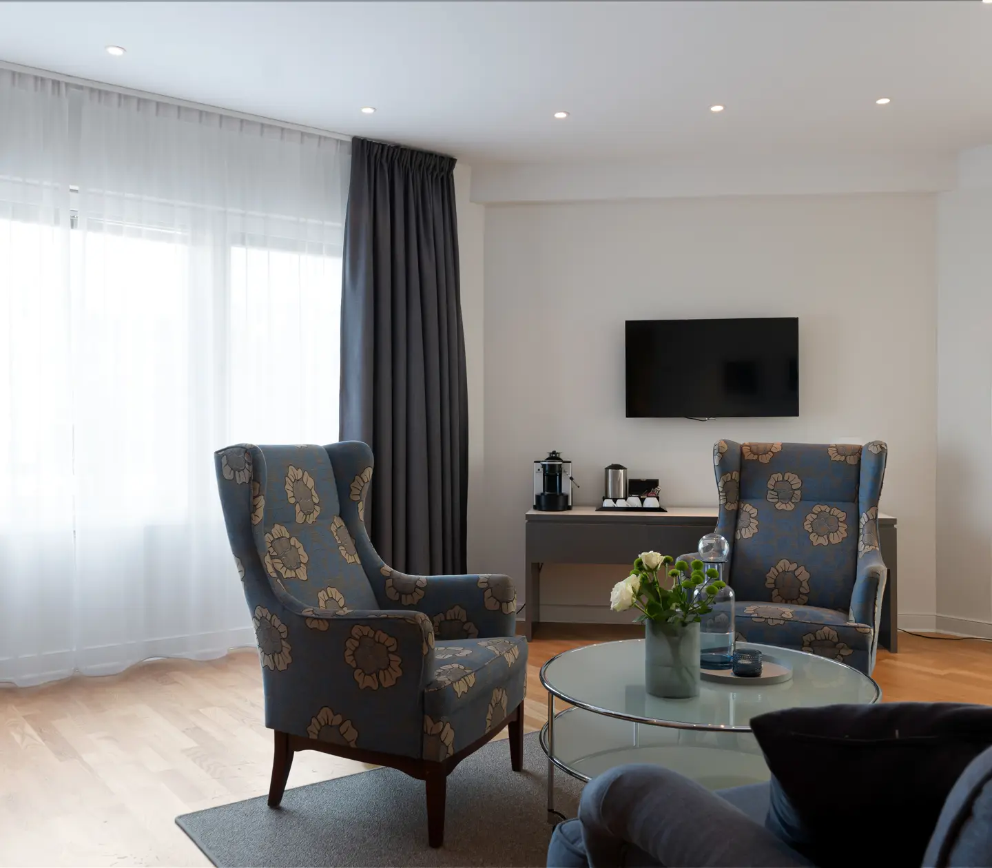 Ljus hotellsvit med soffgrupp, tv och fönster