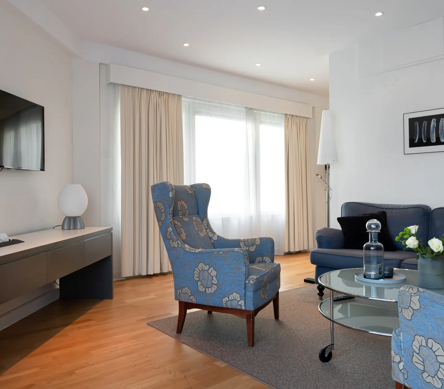 Ljus hotellsvit med soffgrupp, tv och fönster