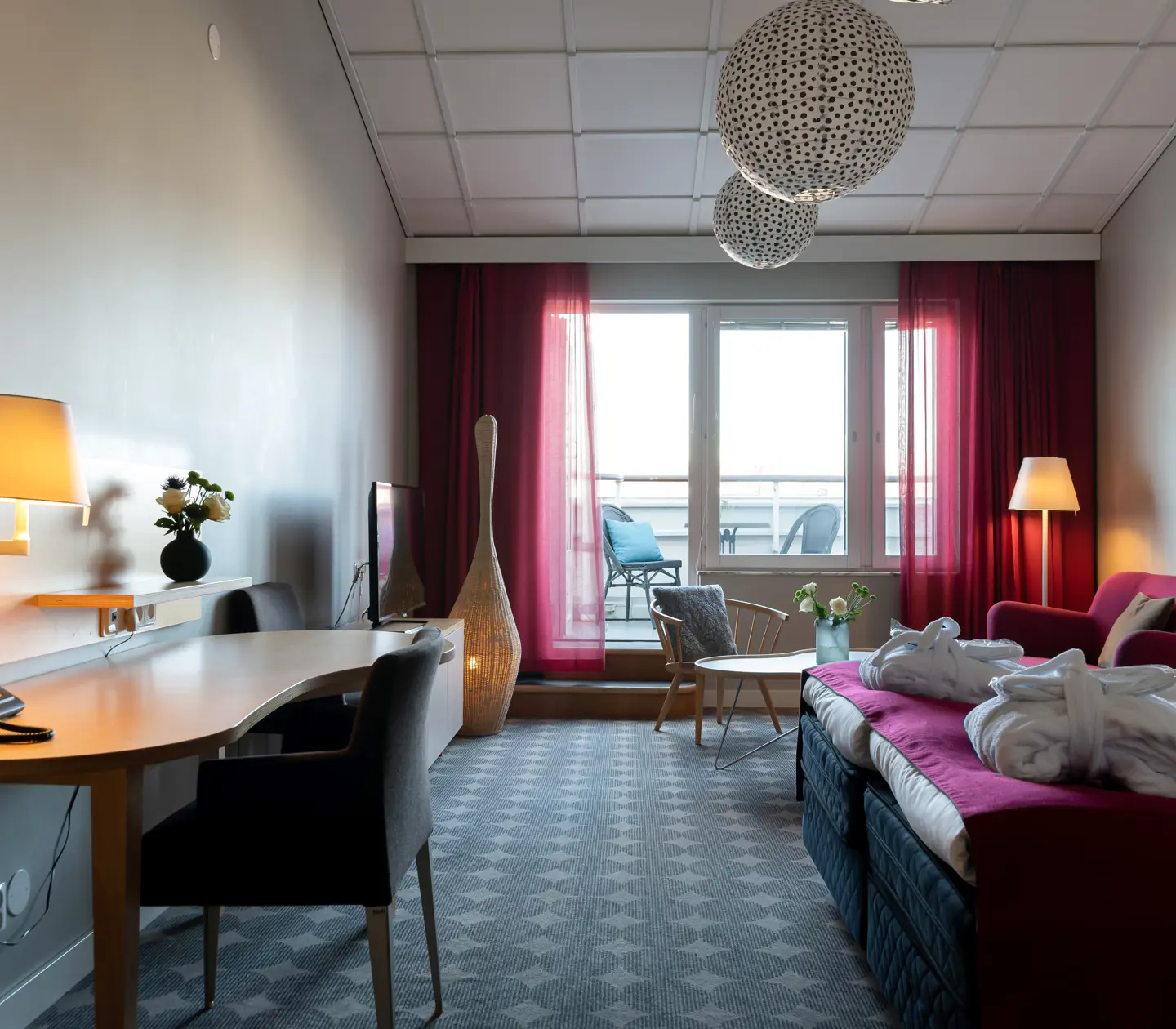 Mysig hotellsvit med soffa, skrivbord och balkong