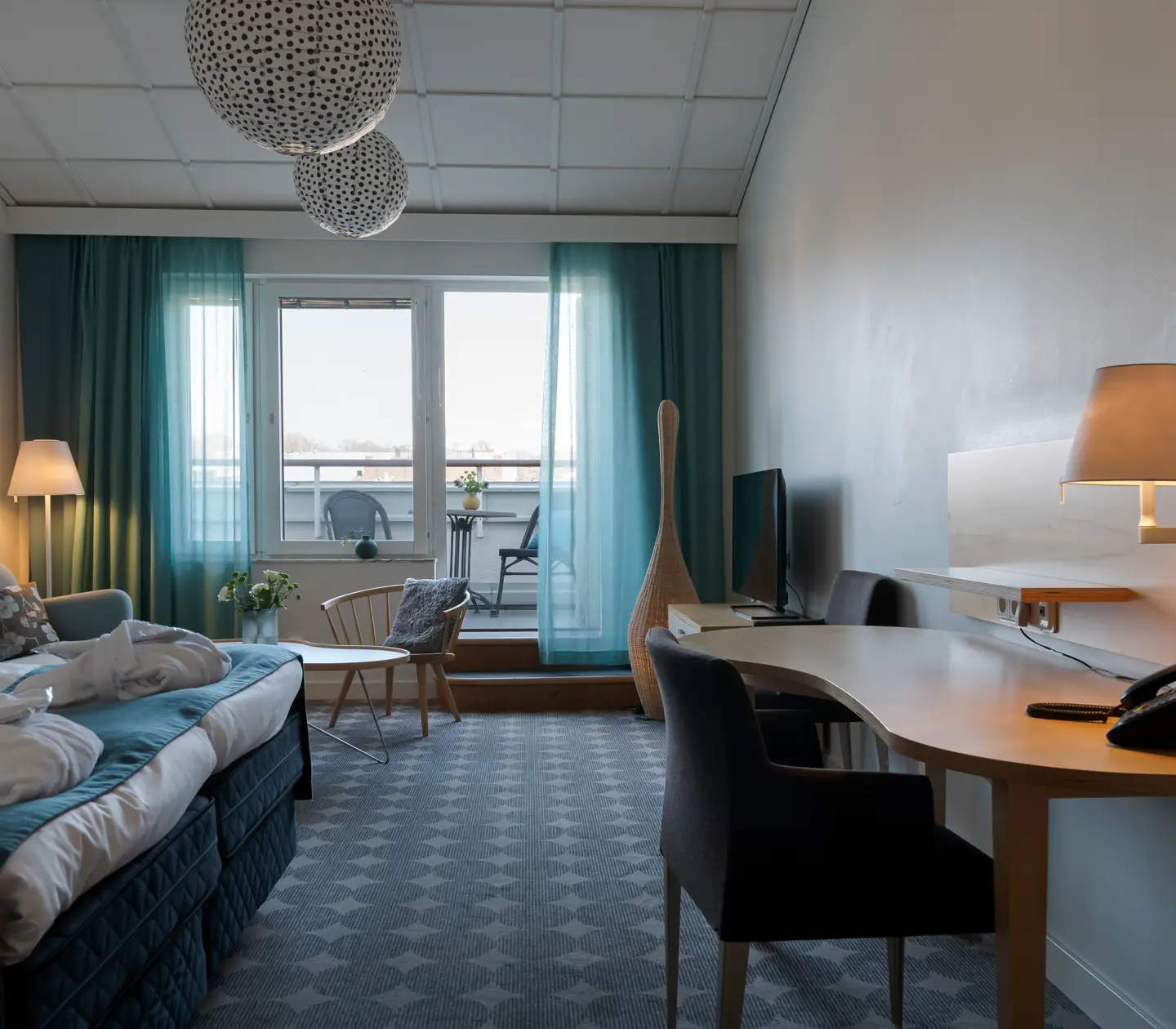 Ljus hotellsvit med soffa, balkong och skrivbord