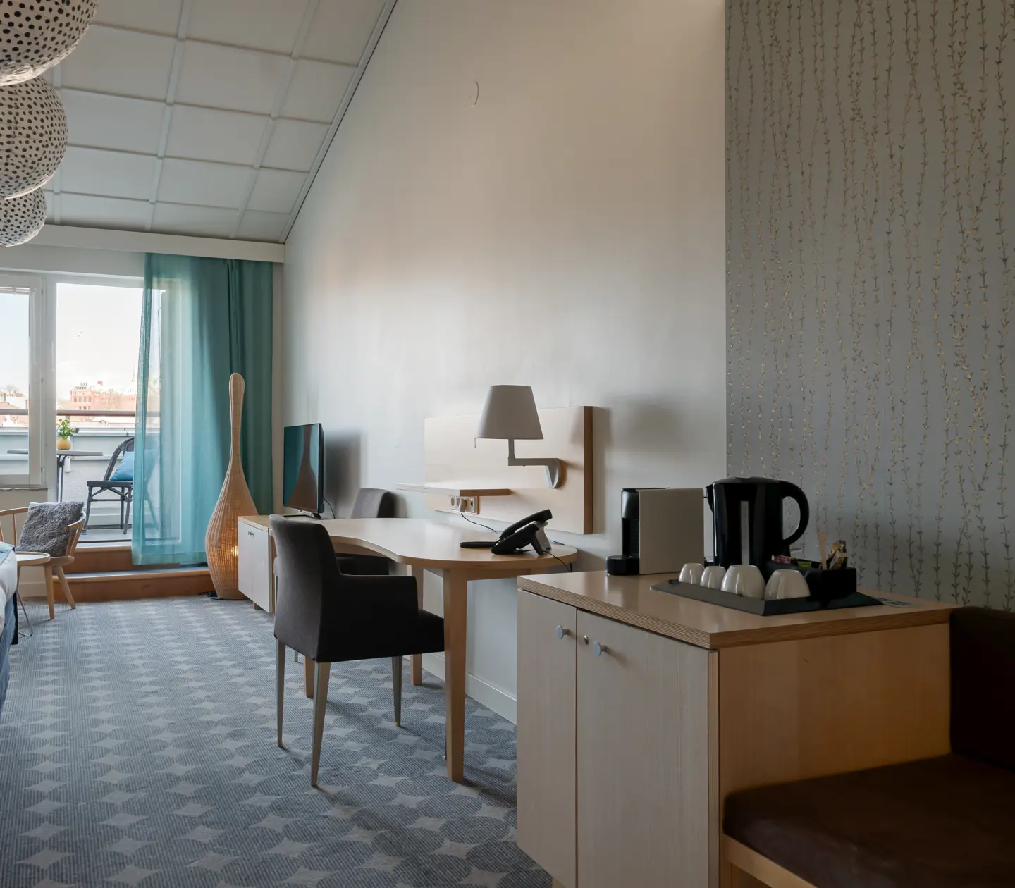 Ljus hotellsvit med balkong, blå gardiner och skrivbord
