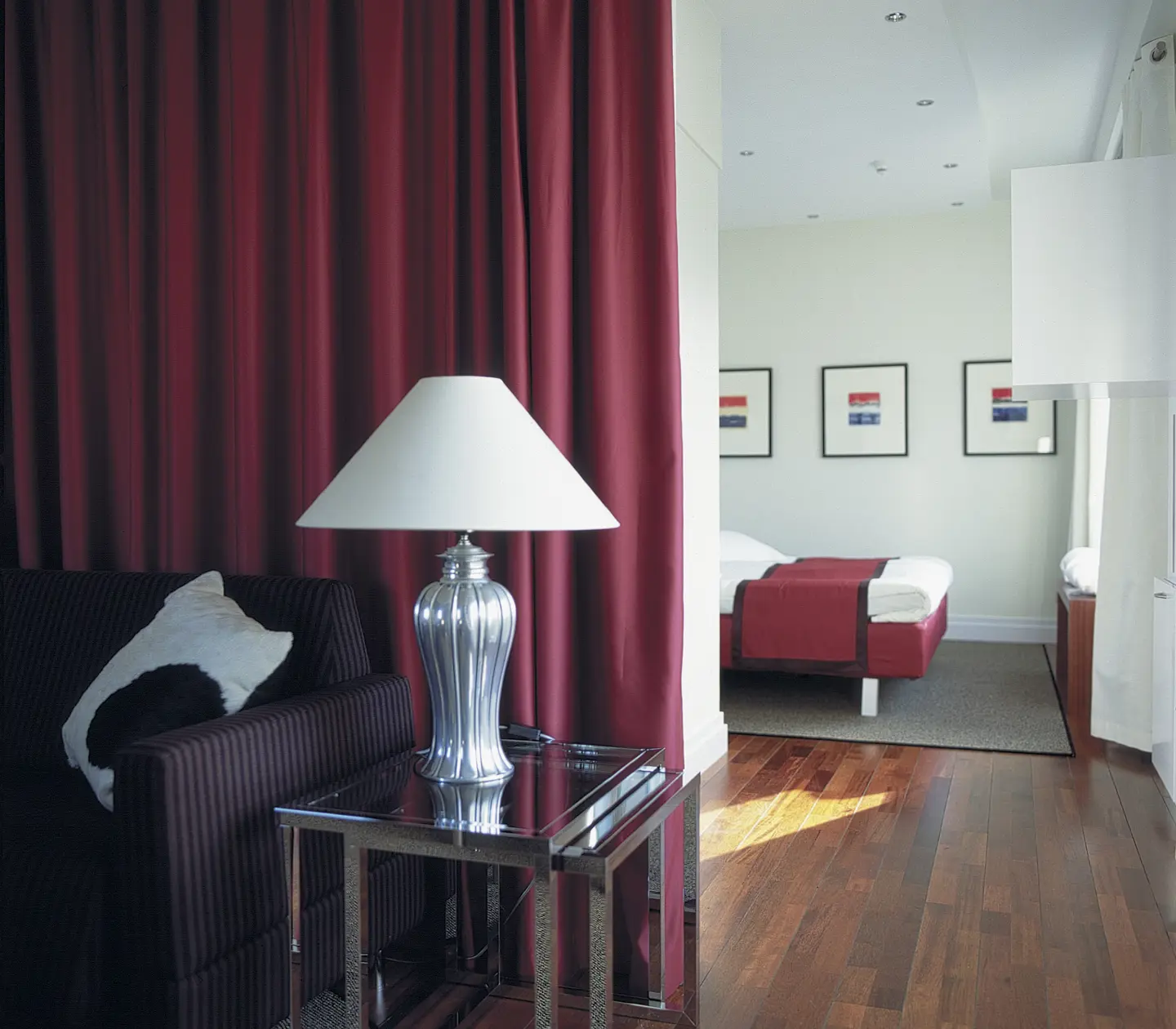 Hotellsvit med säng, bordslampa och tavlor