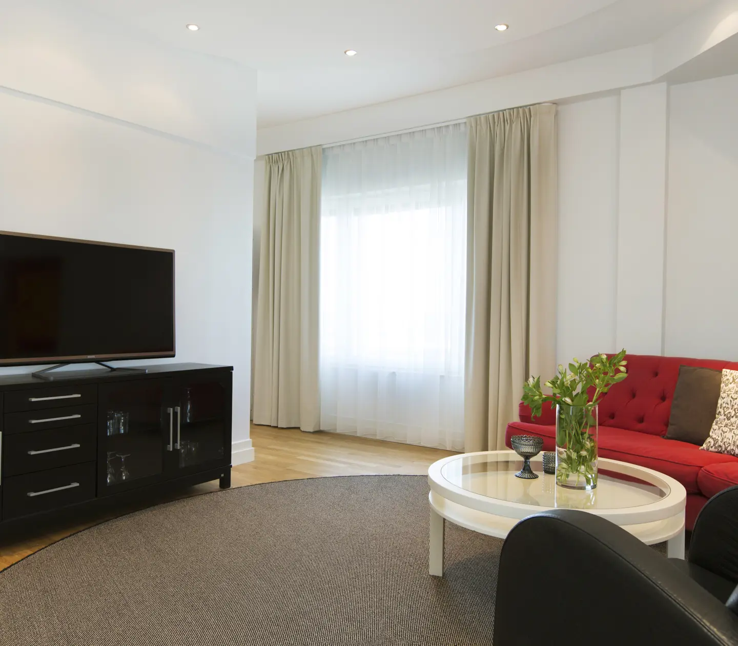 Ljus hotellsvit med soffgrupp, tv och fönster