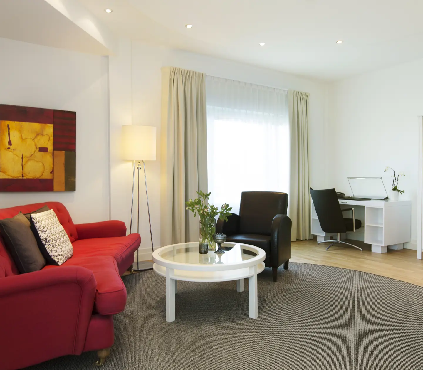 Ljus hotellsvit med soffgrupp, skrivbord och fönster