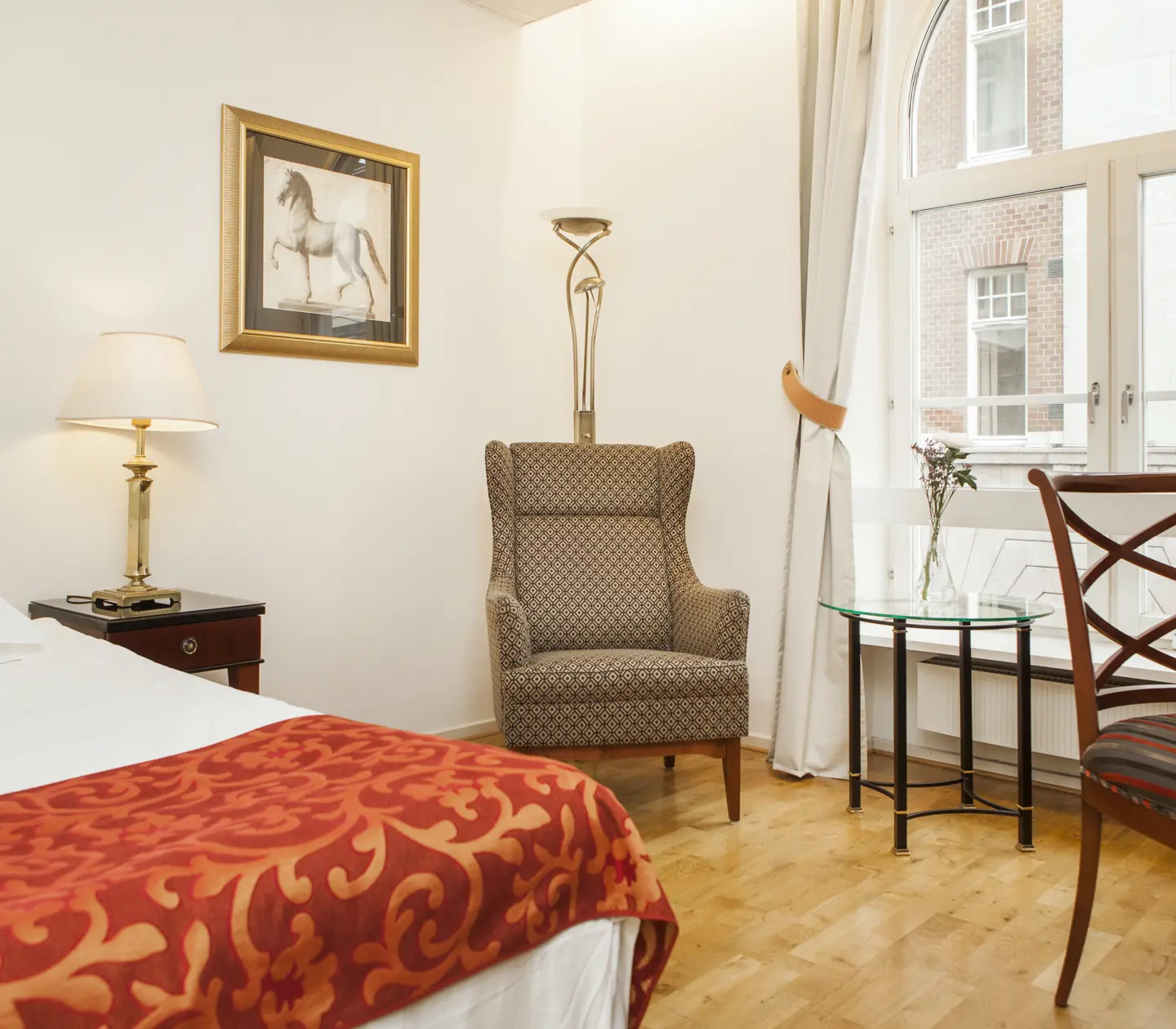 Ljust hotellrum med säng, fåtölj och fönster