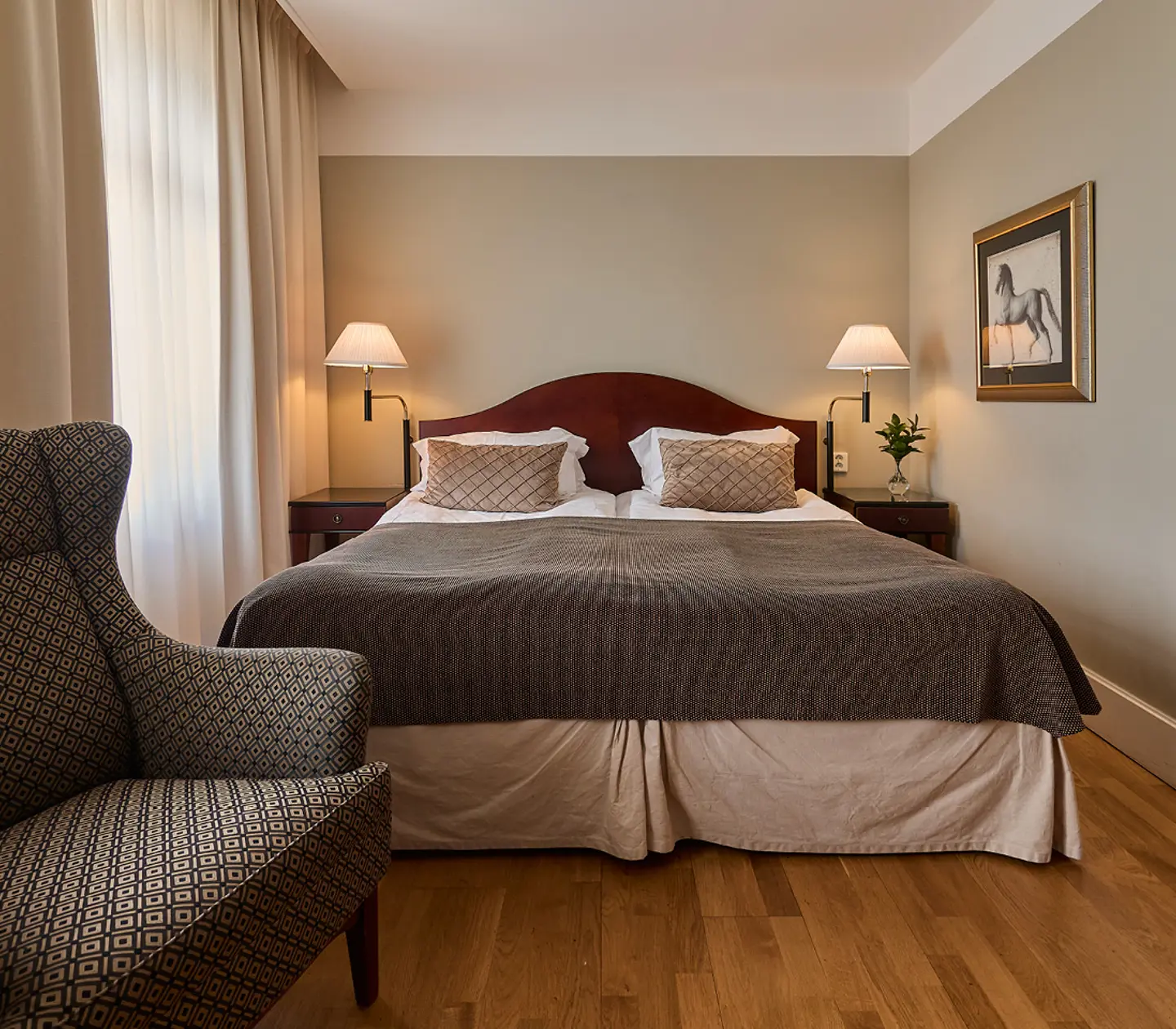 Hotellrum med skrivbord, fåtölj och gardiner