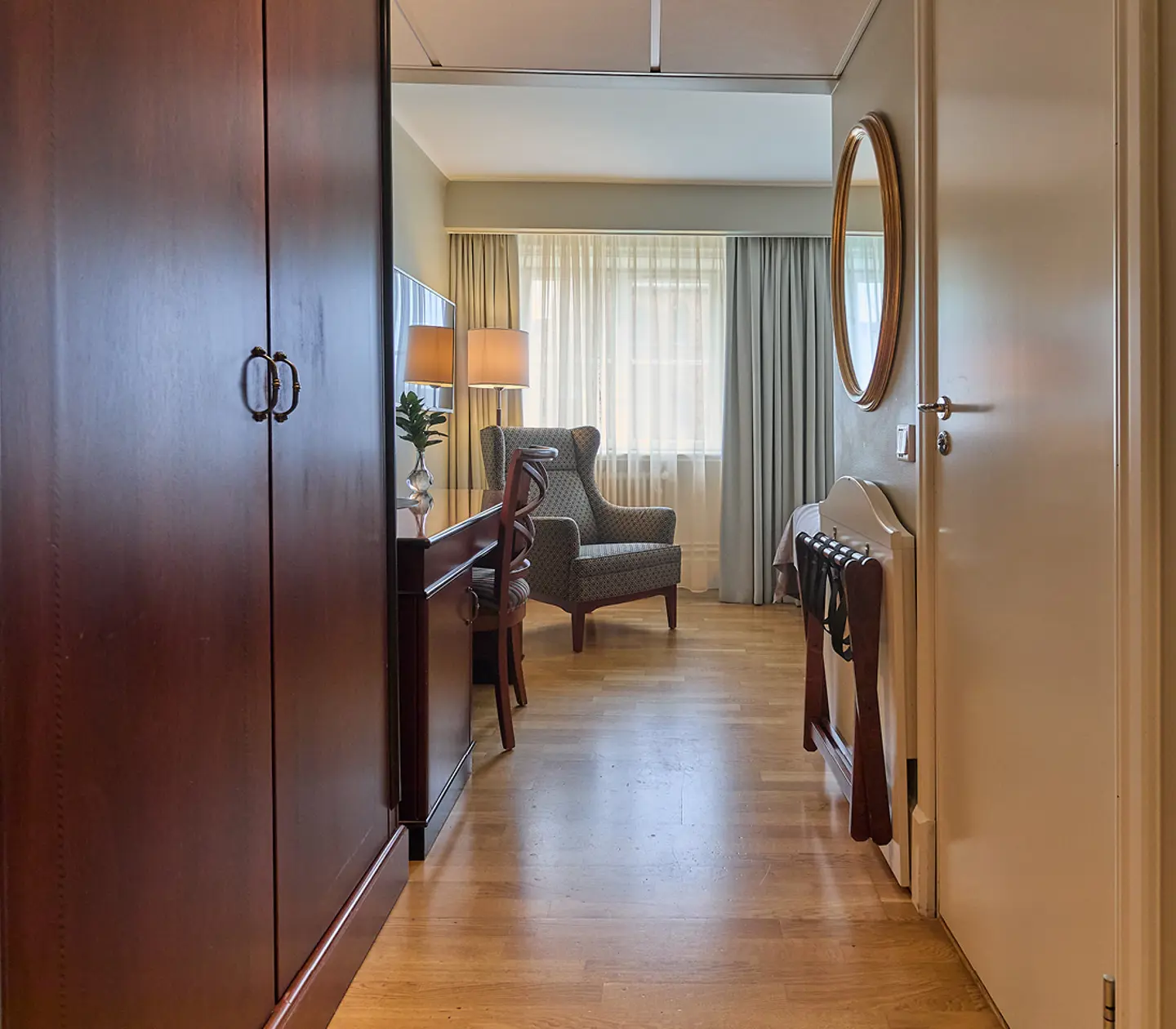Hotellrum med skrivbord, fåtölj, garderob och tv