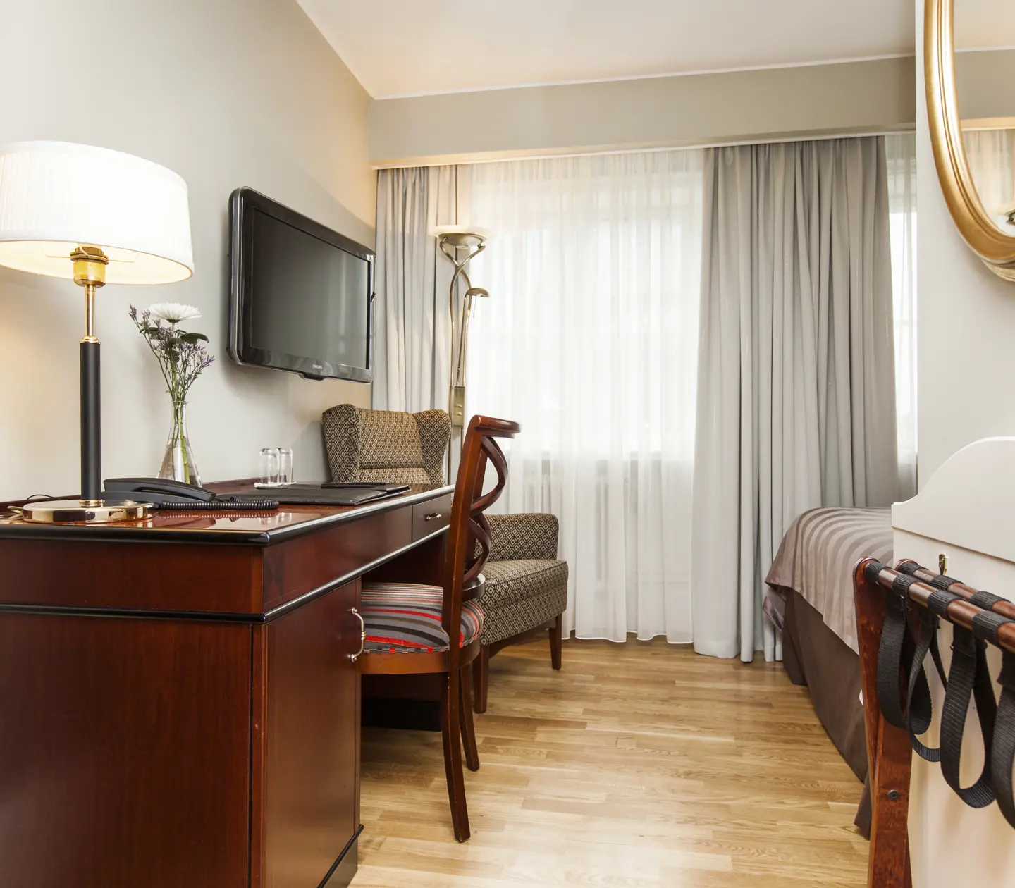Hotellrum med skrivbord, fåtölj och gardiner