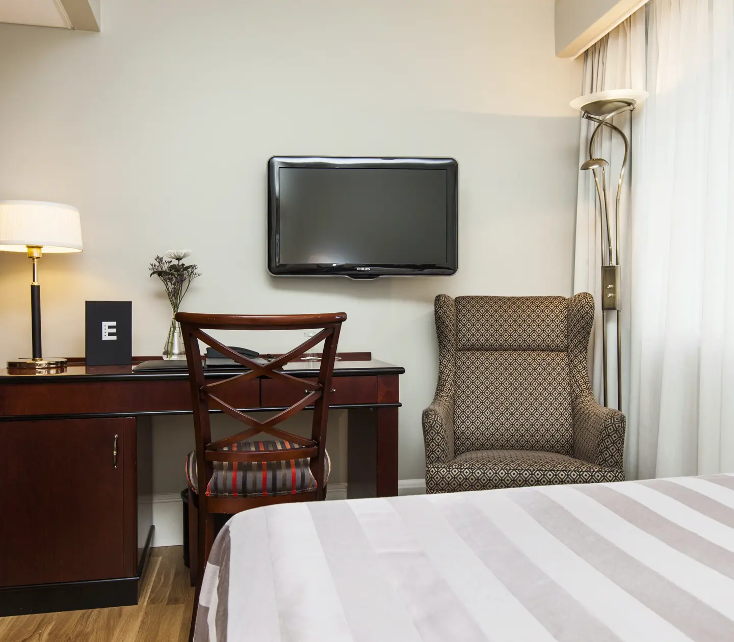 Hotellrum med skrivbord, fåtölj och tv