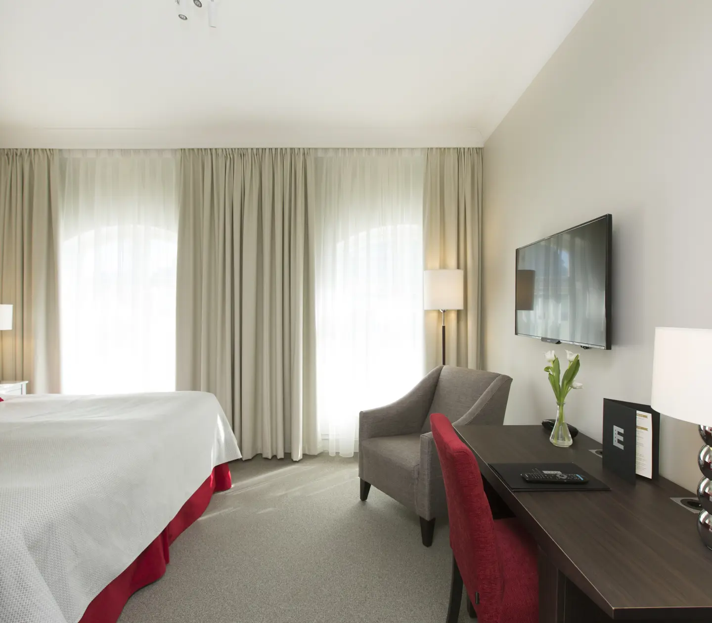 Hotellrum med dubbelsäng, skrivbord och fåtölj