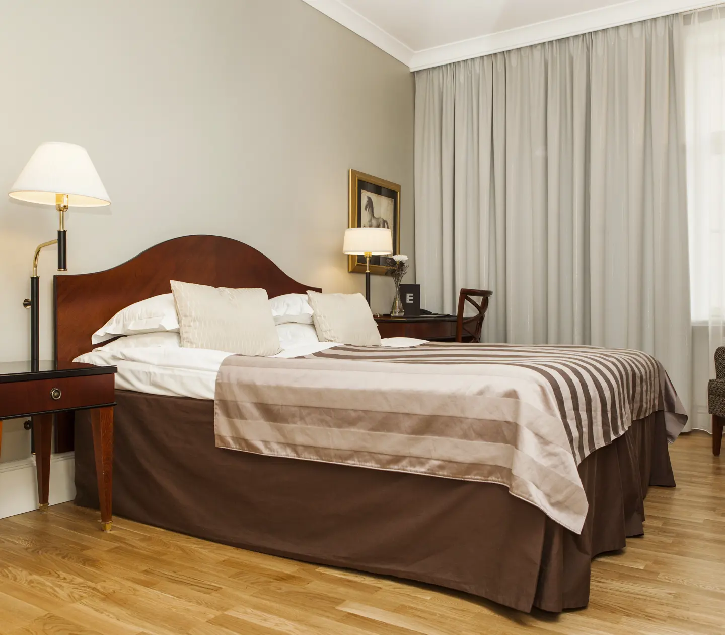 Hotellrum med dubbelsäng, skrivbord och gardiner
