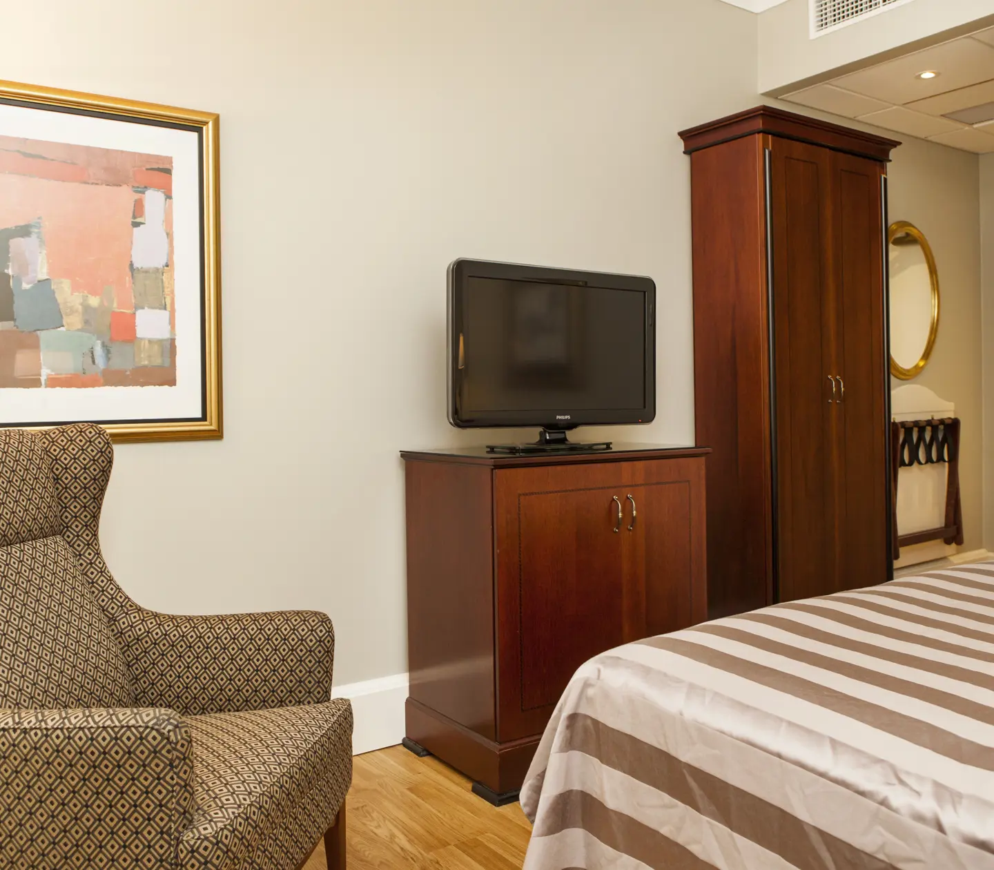 Hotellrum med fåtölj, garderob och tv