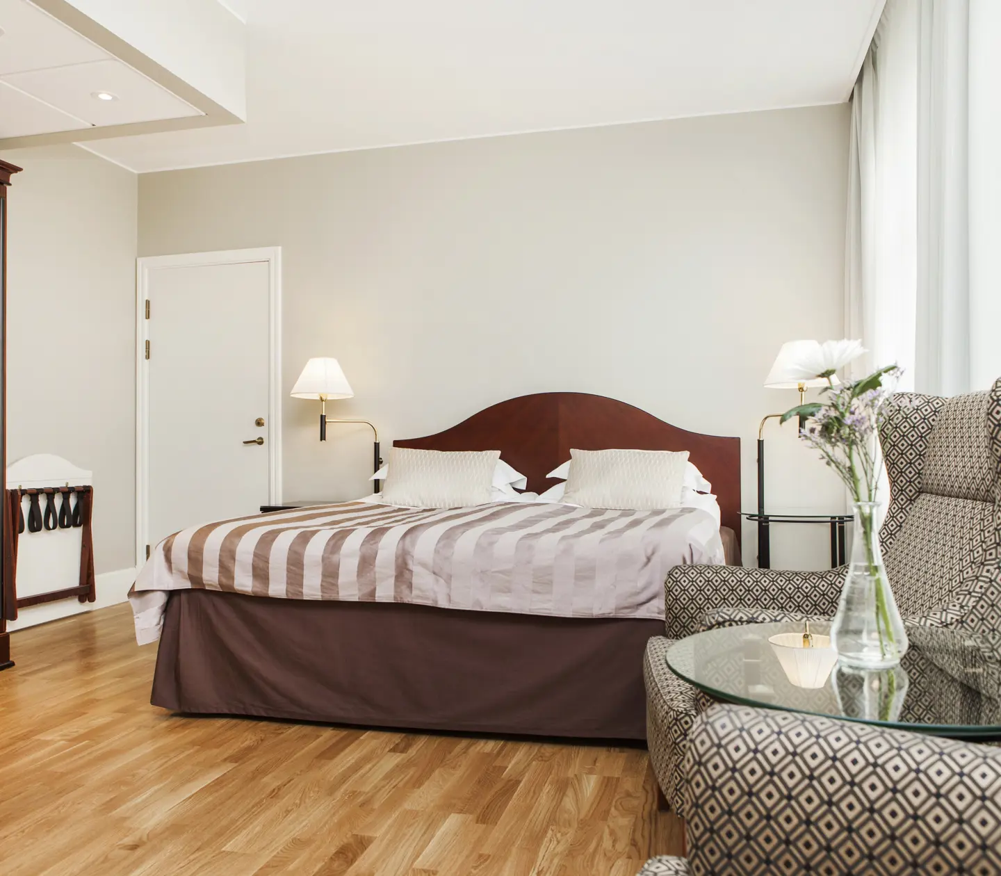 Hotel room with double bed, armchairs and bedside lamps