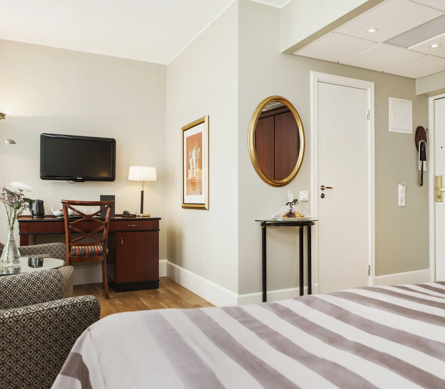 Hotel room with double bed, armchairs and desk