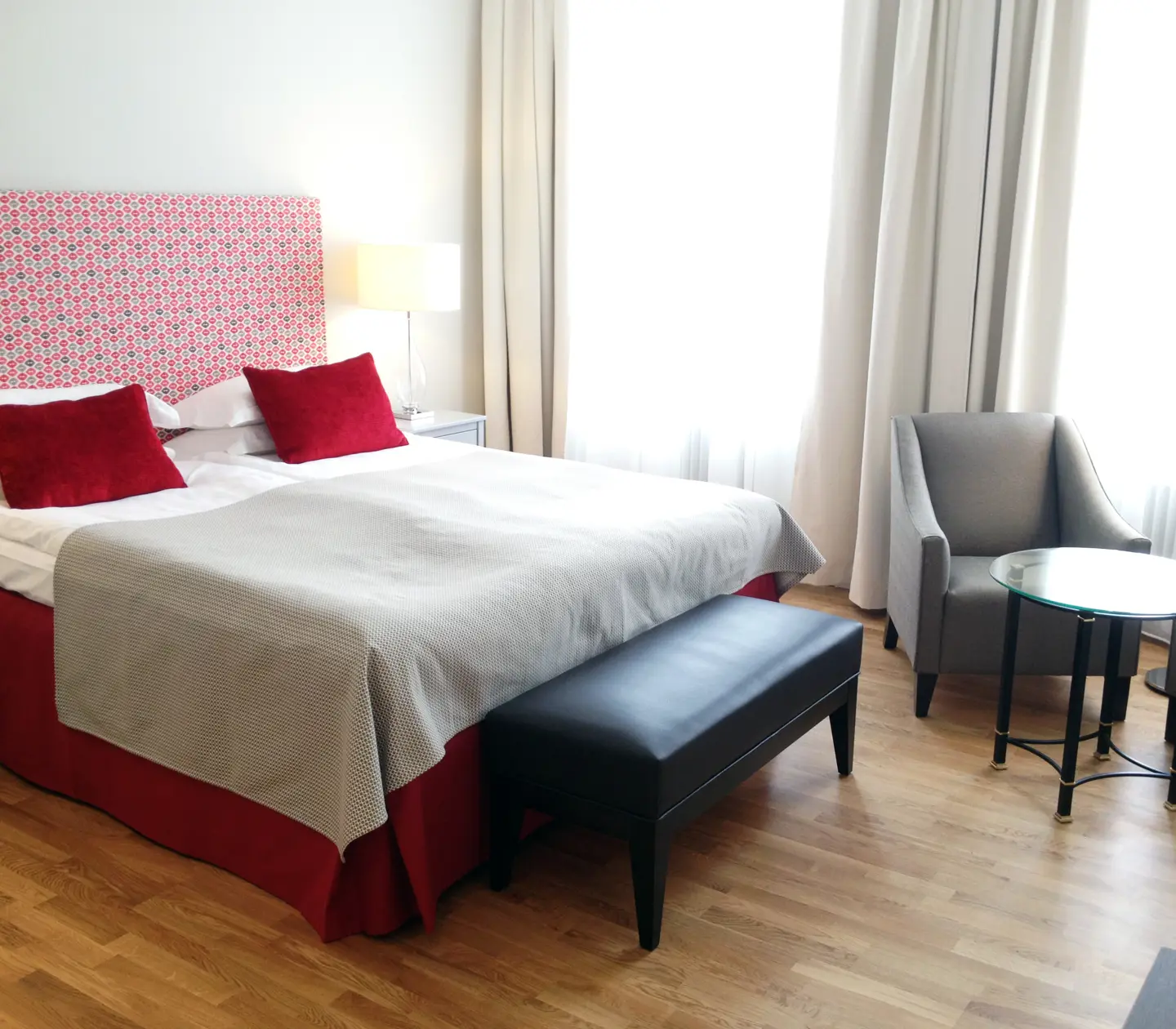Hotel room with double bed, red headboard and armchairs