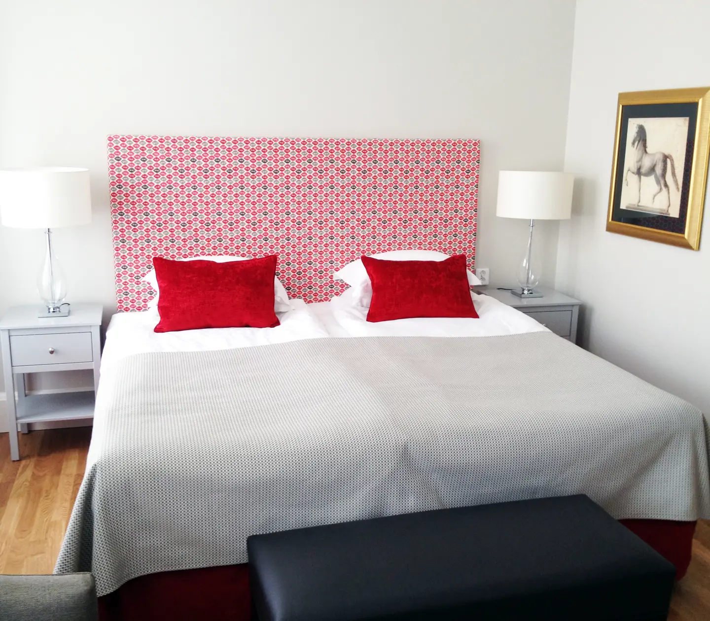 Hotel room with double bed, red headboard and bedside table