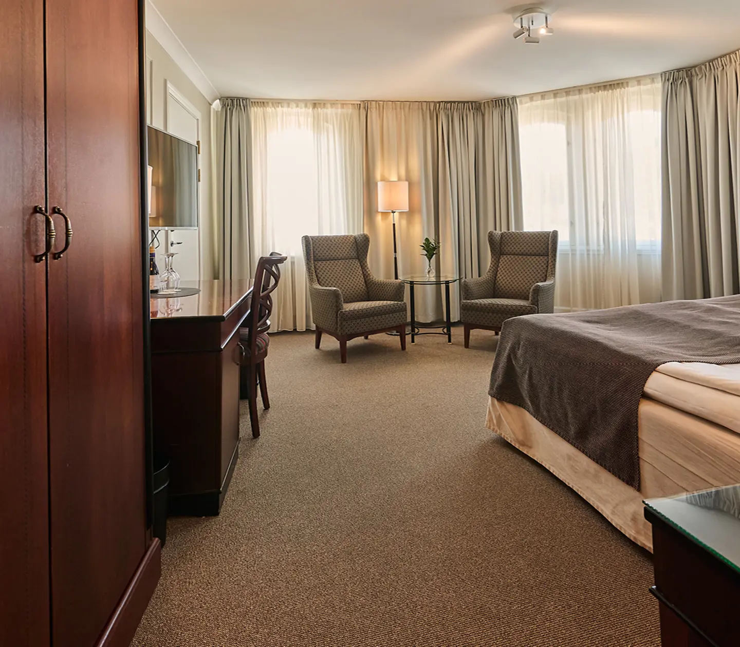 Hotel room with double bed, armchairs and bedside lamps
