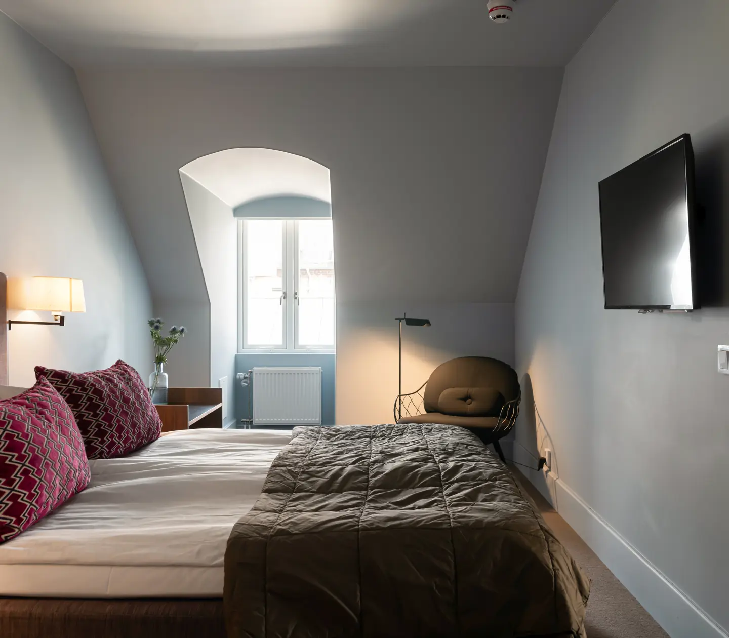 Svit med dubbelsäng, sänglampor och snedväggar