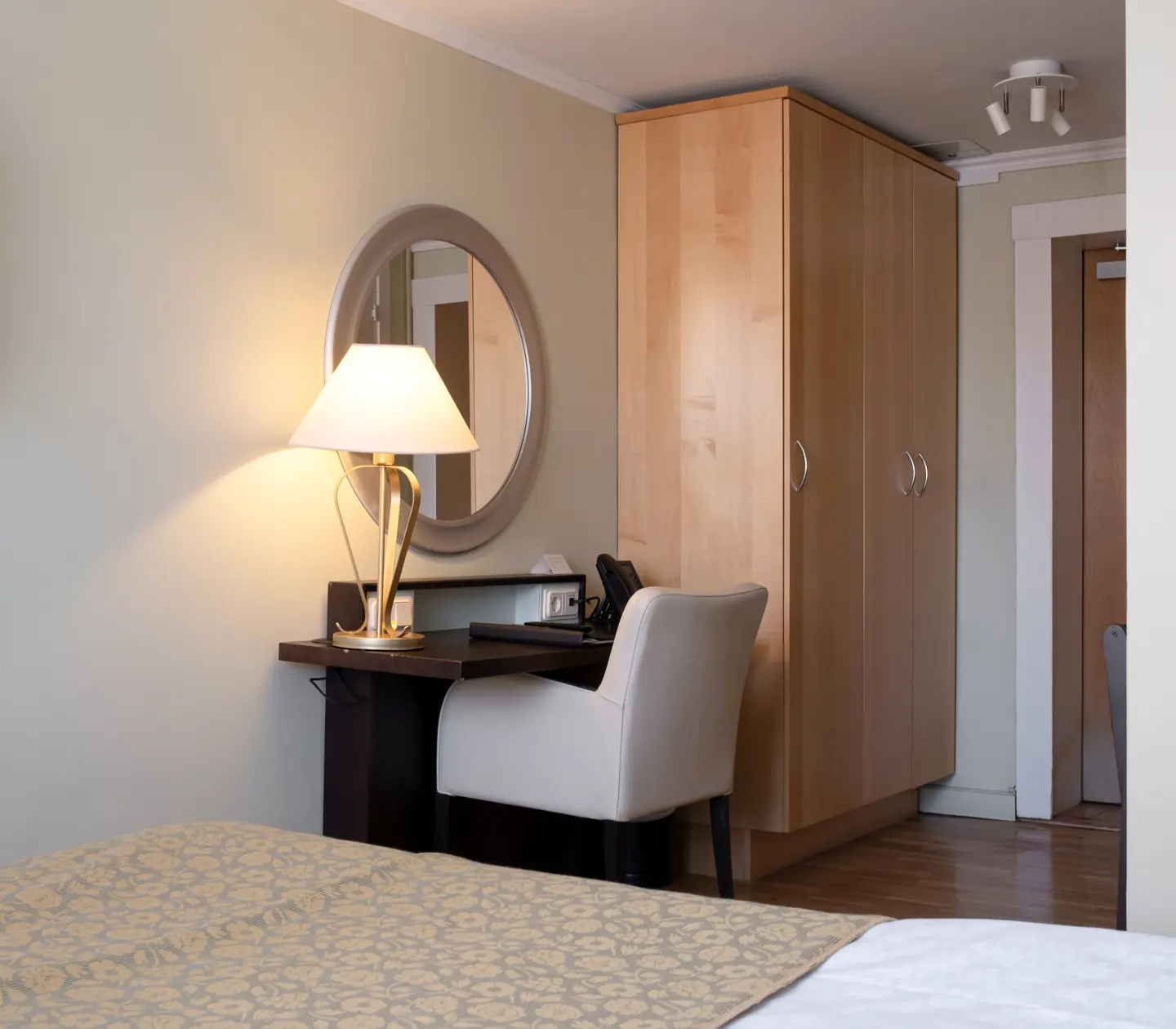 Hotellrum med skrivbord, rund spegel och garderob