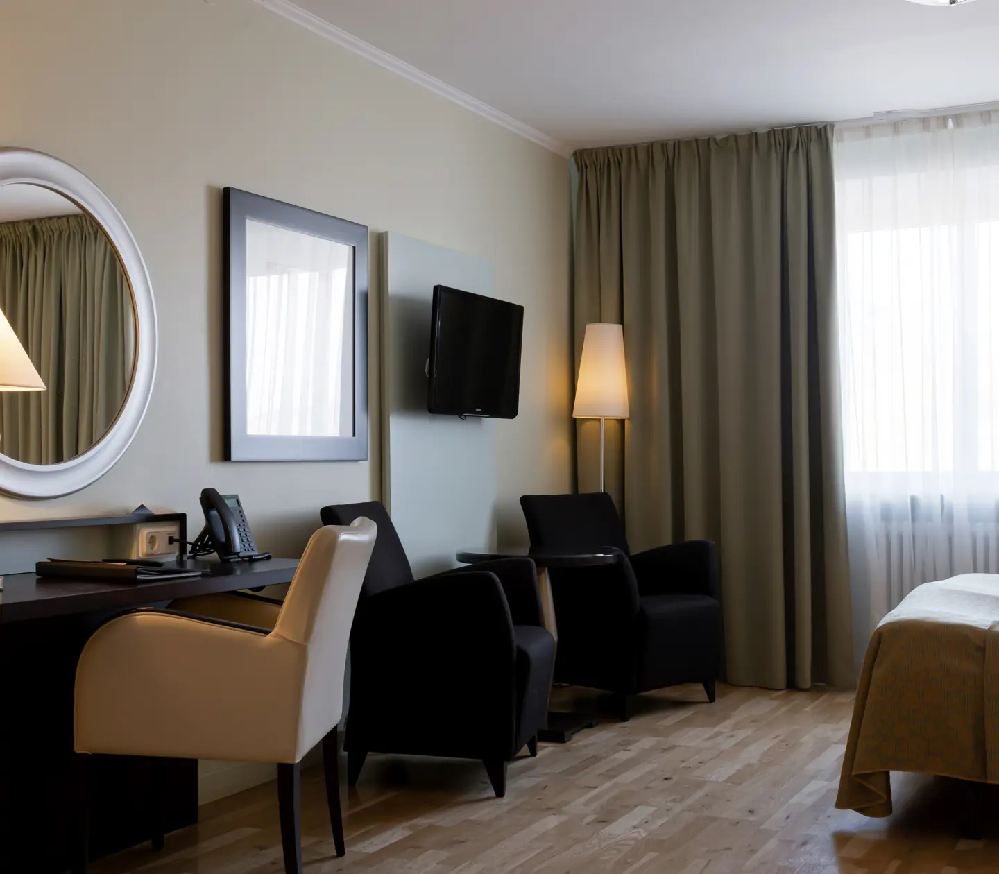 Hotellrum med skrivbord, fåtöljer och fönster