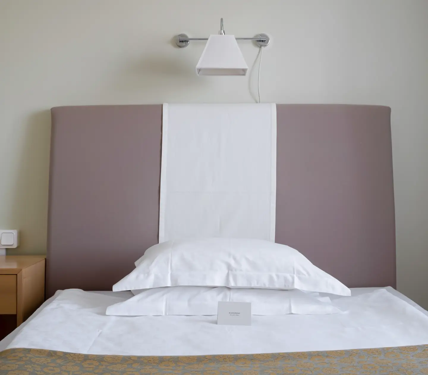 Hotellrum med säng, sänglampa och nattduksbord