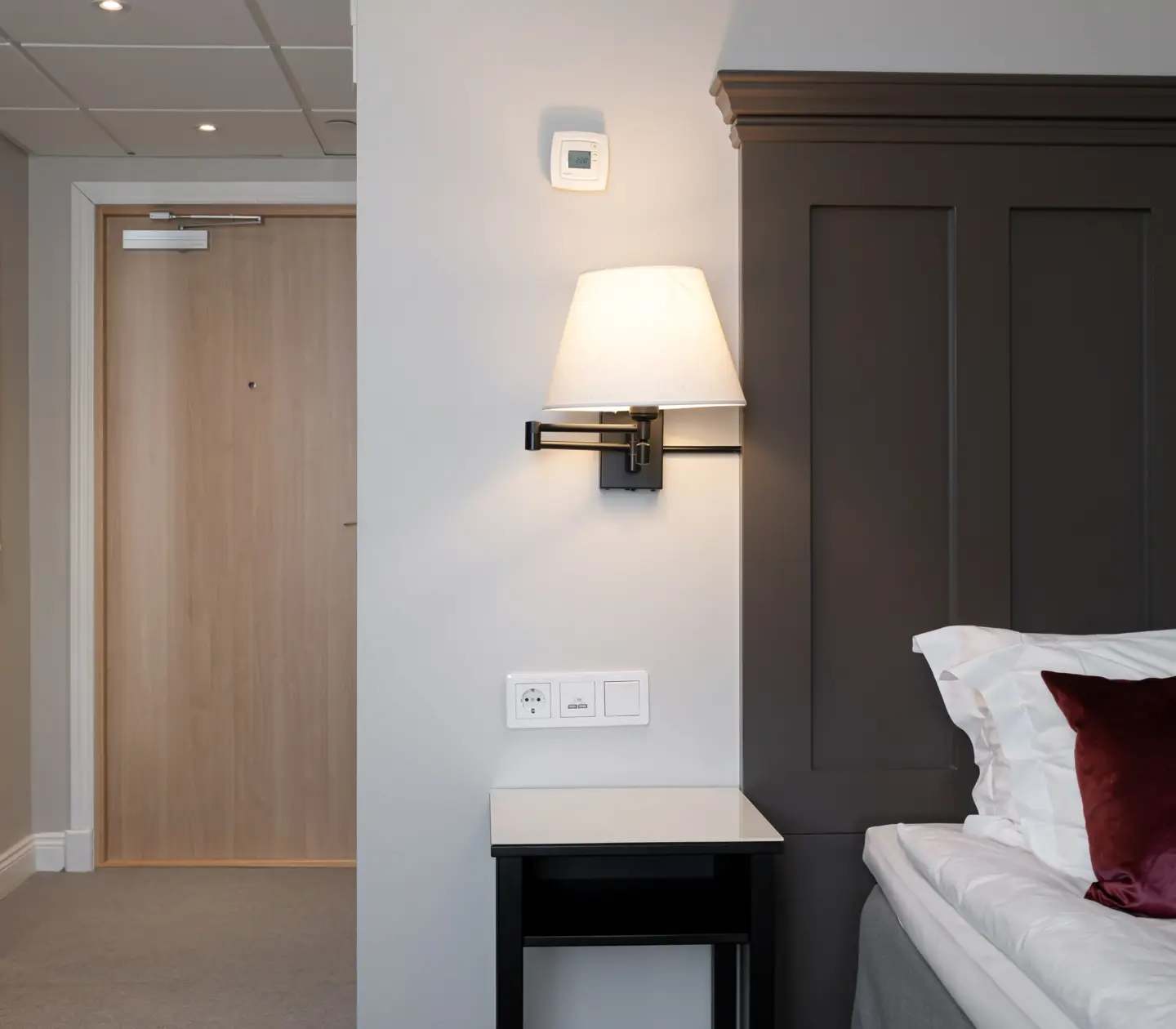 Hotellrum med säng, sänglampa och spegel