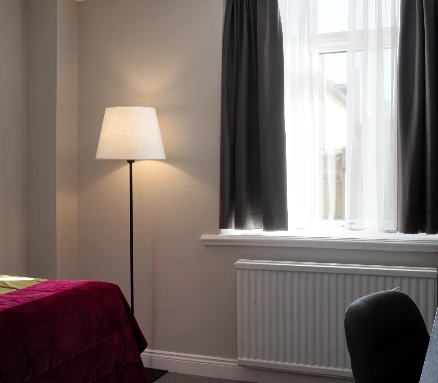Hotellrum med fönster, golvlampa och skrivbord