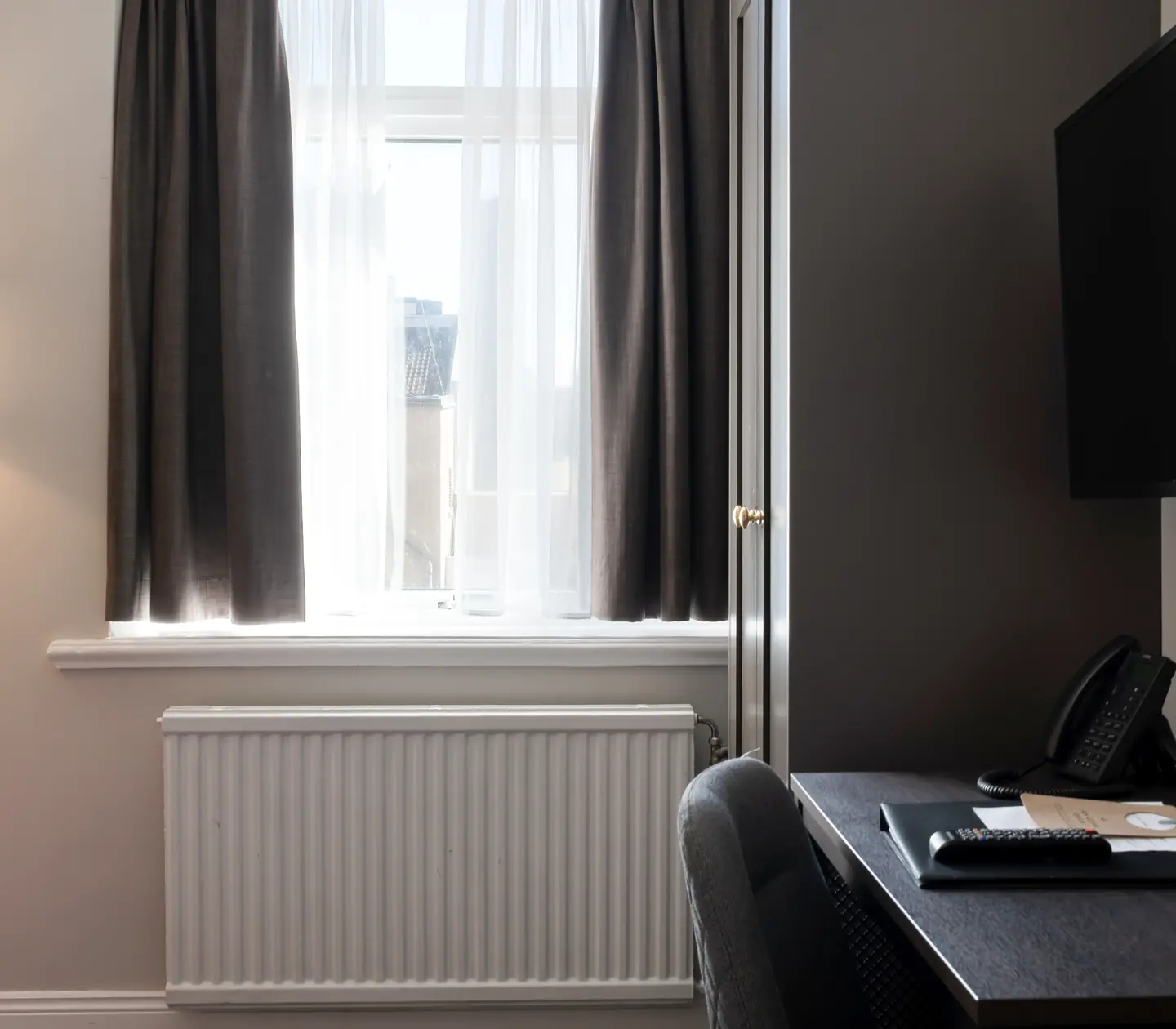 Hotellrum med fönster, skrivbord och garderob