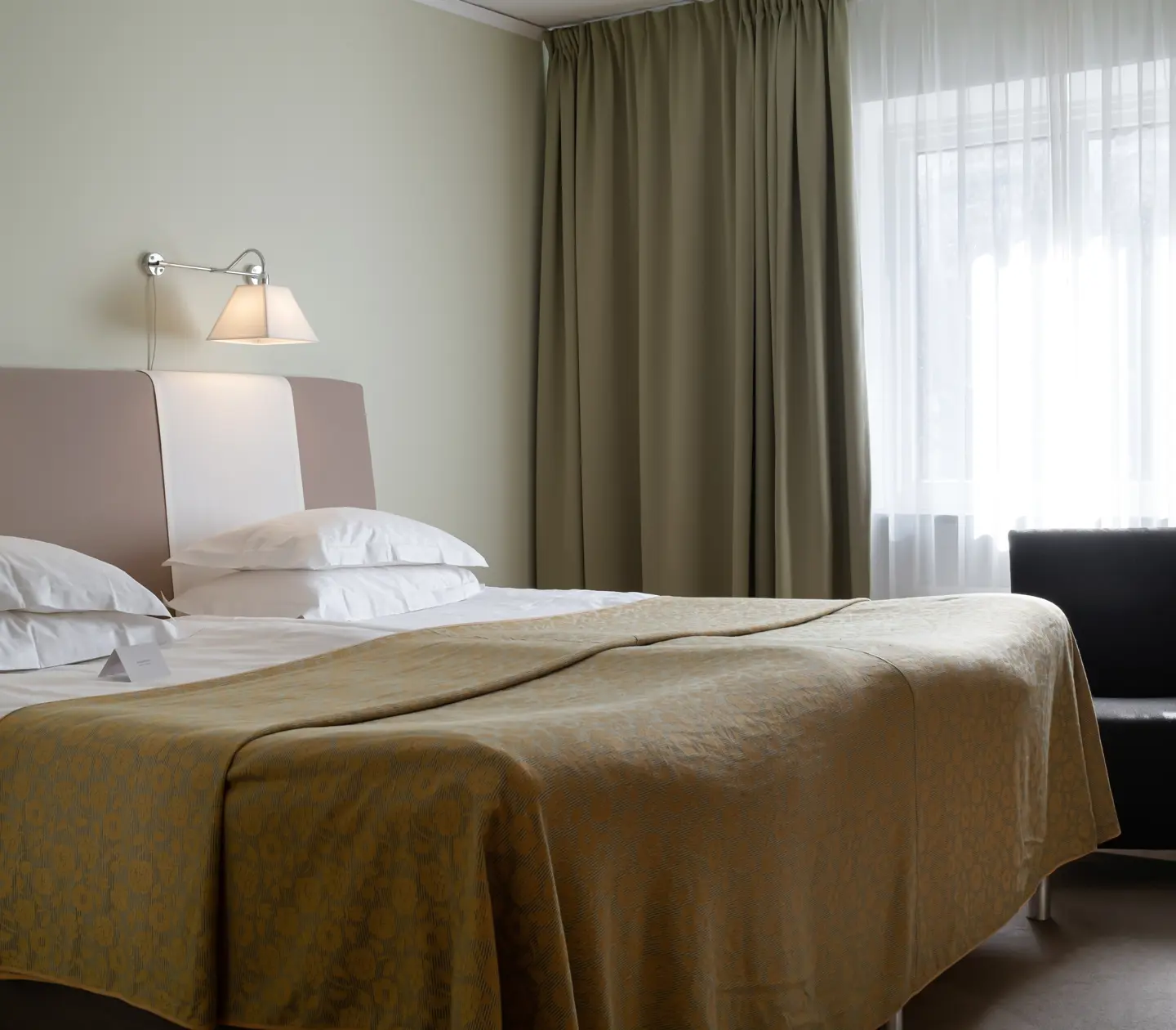 Hotellrum med säng, fåtölj och gardiner