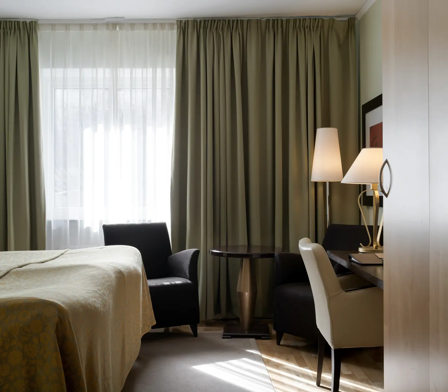 Hotellrum med säng, fåtöljer och skrivbord