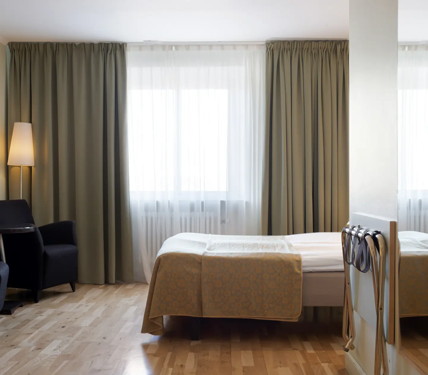 Hotellrum med säng, fåtöljer och fönster