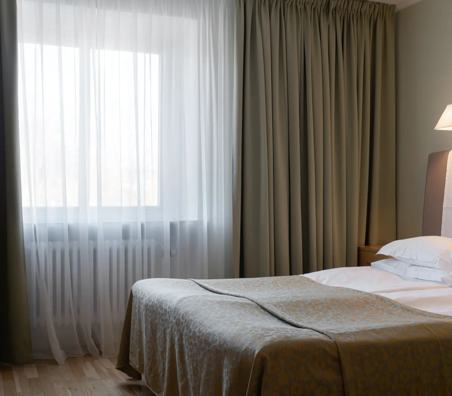 Hotellrum med säng, sänglampa och fönster