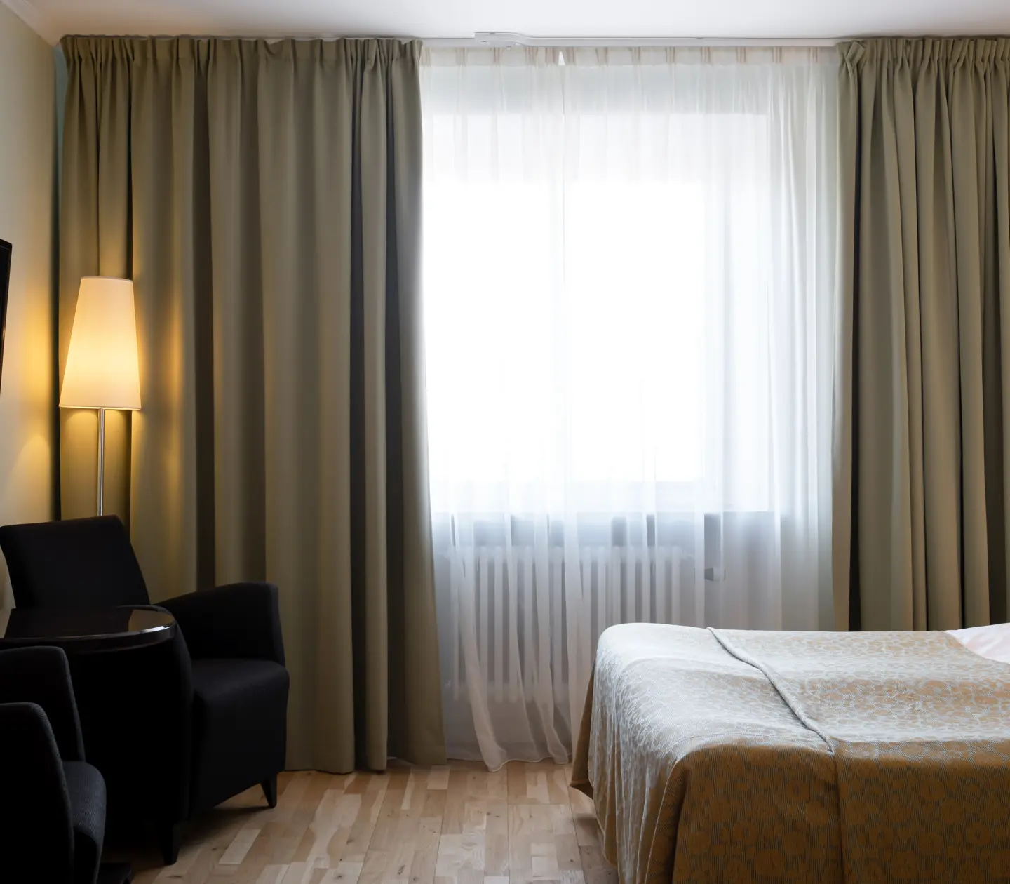 Hotellrum med säng, fåtöljer och fönster