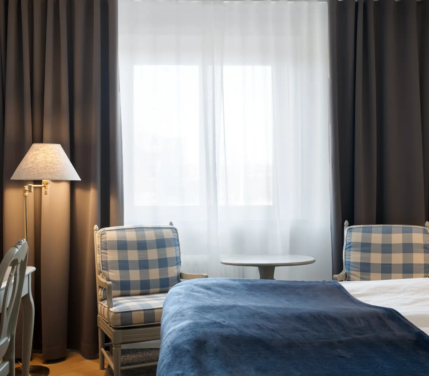 Hotellrum med säng, fåtöljer och fönster