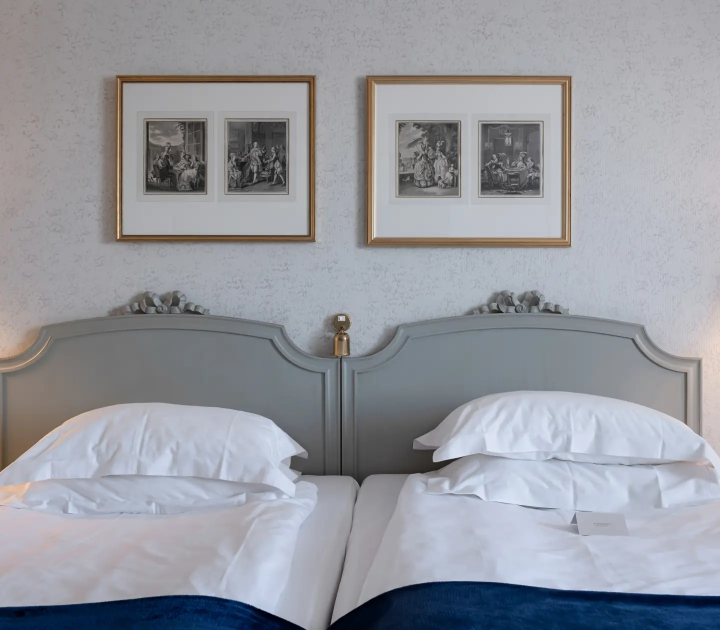 Hotellrum med säng, sänglampa och tavlor