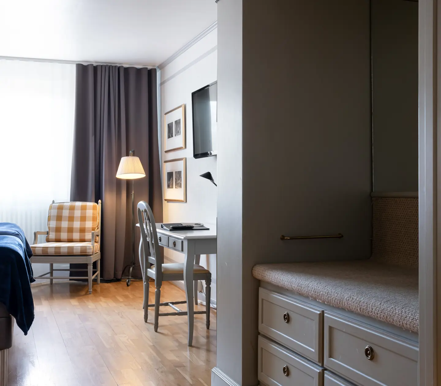 Hotellrum med skrivbord, fåtöljer och garderob