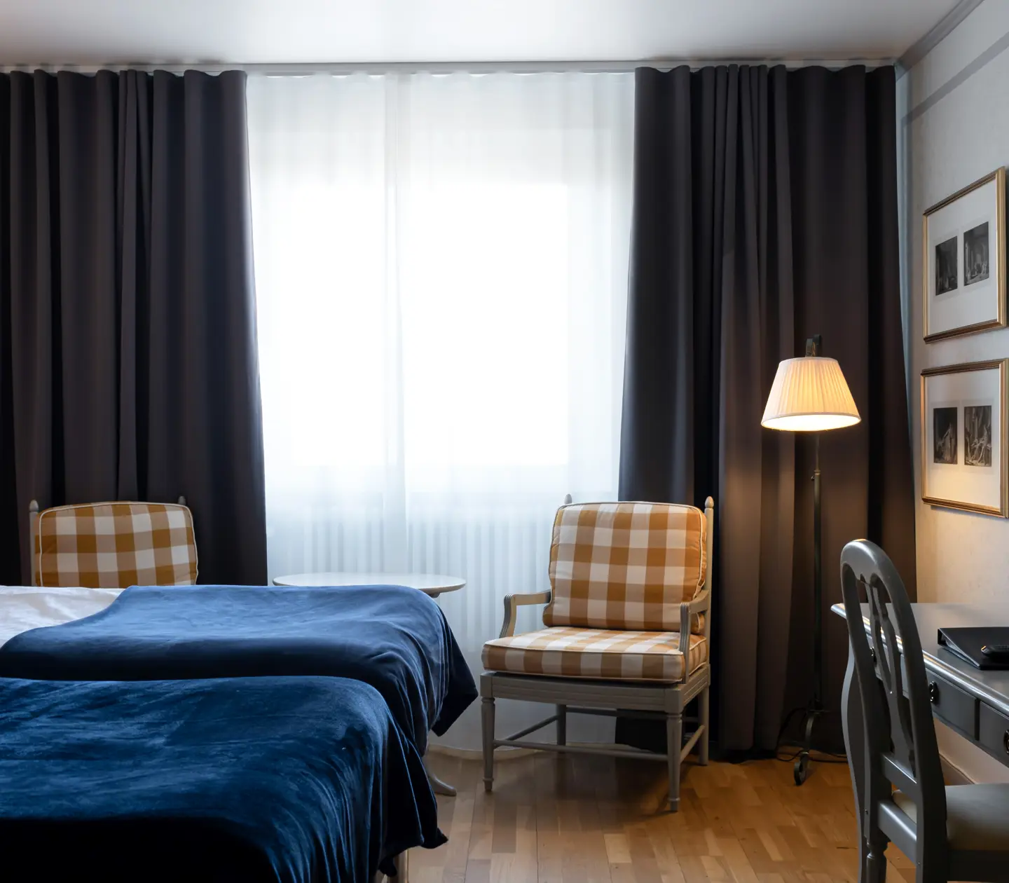 Hotellrum med säng, fåtöljer och skrivbord