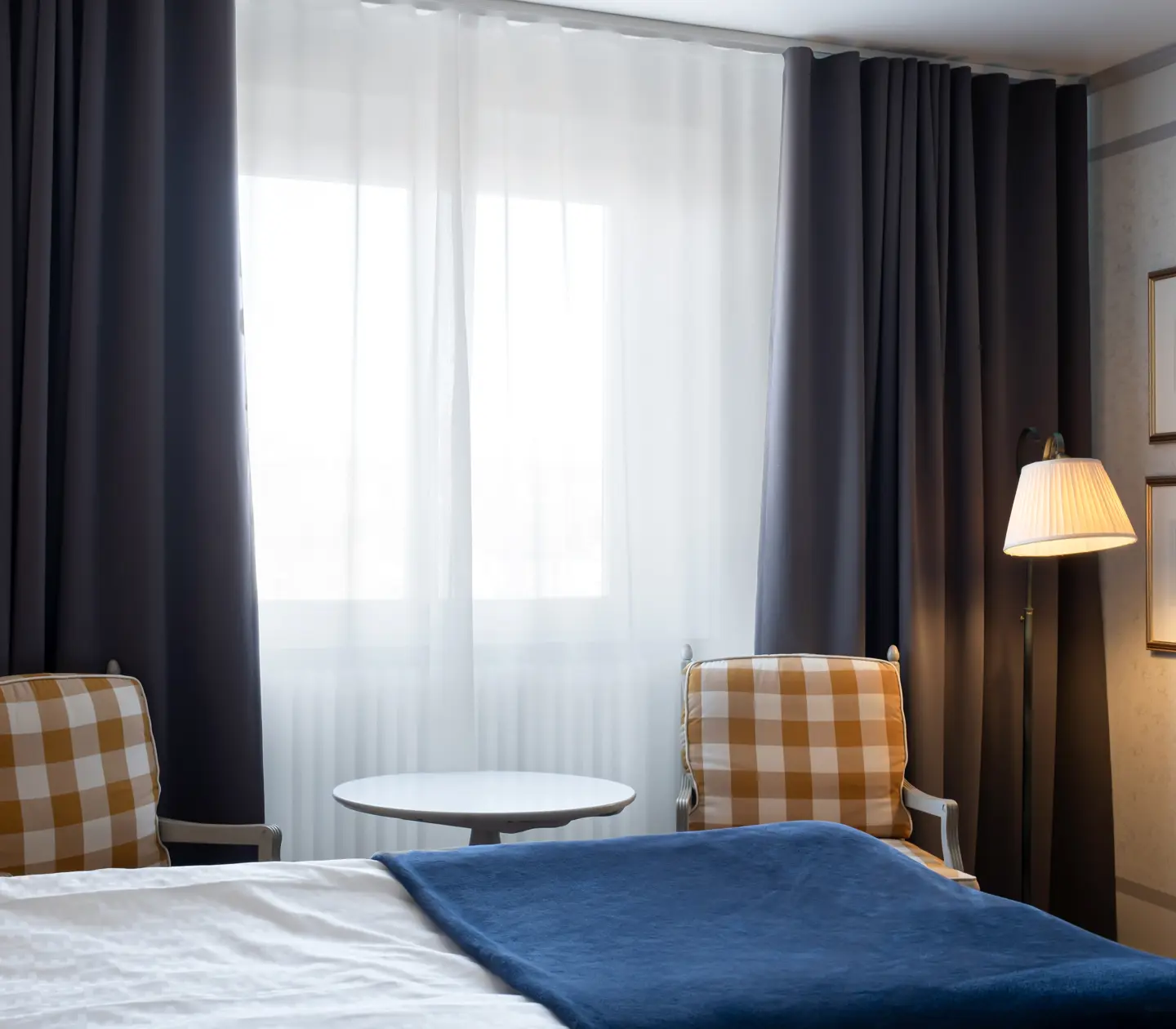 Hotellrum med säng, fåtöljer och fönster