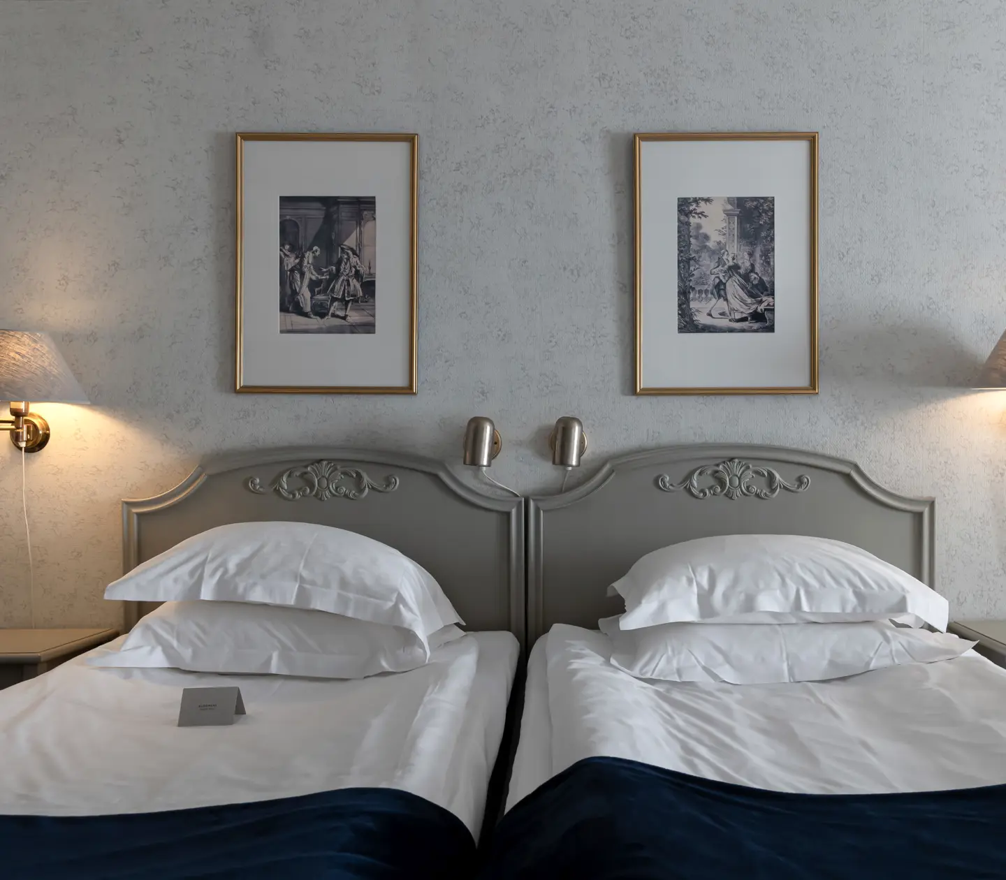 Hotellrum med säng, sänglampor och tavlor