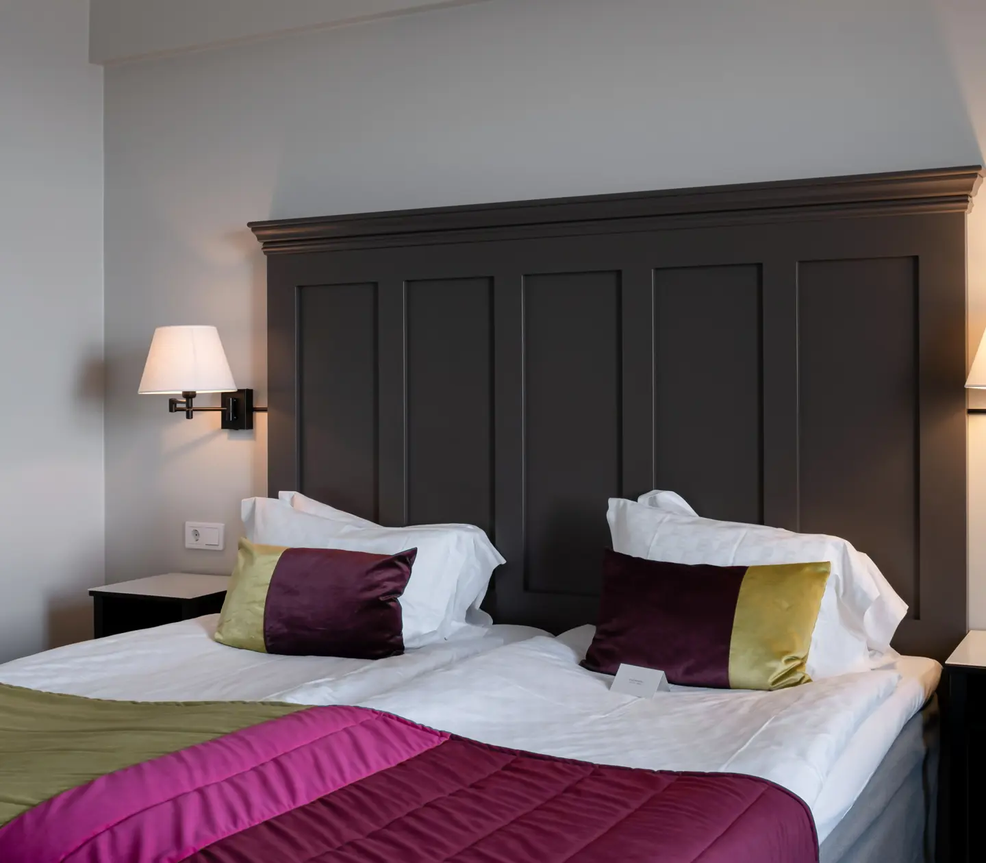 Hotellrum med säng, stor sänggavel i trä och tavla
