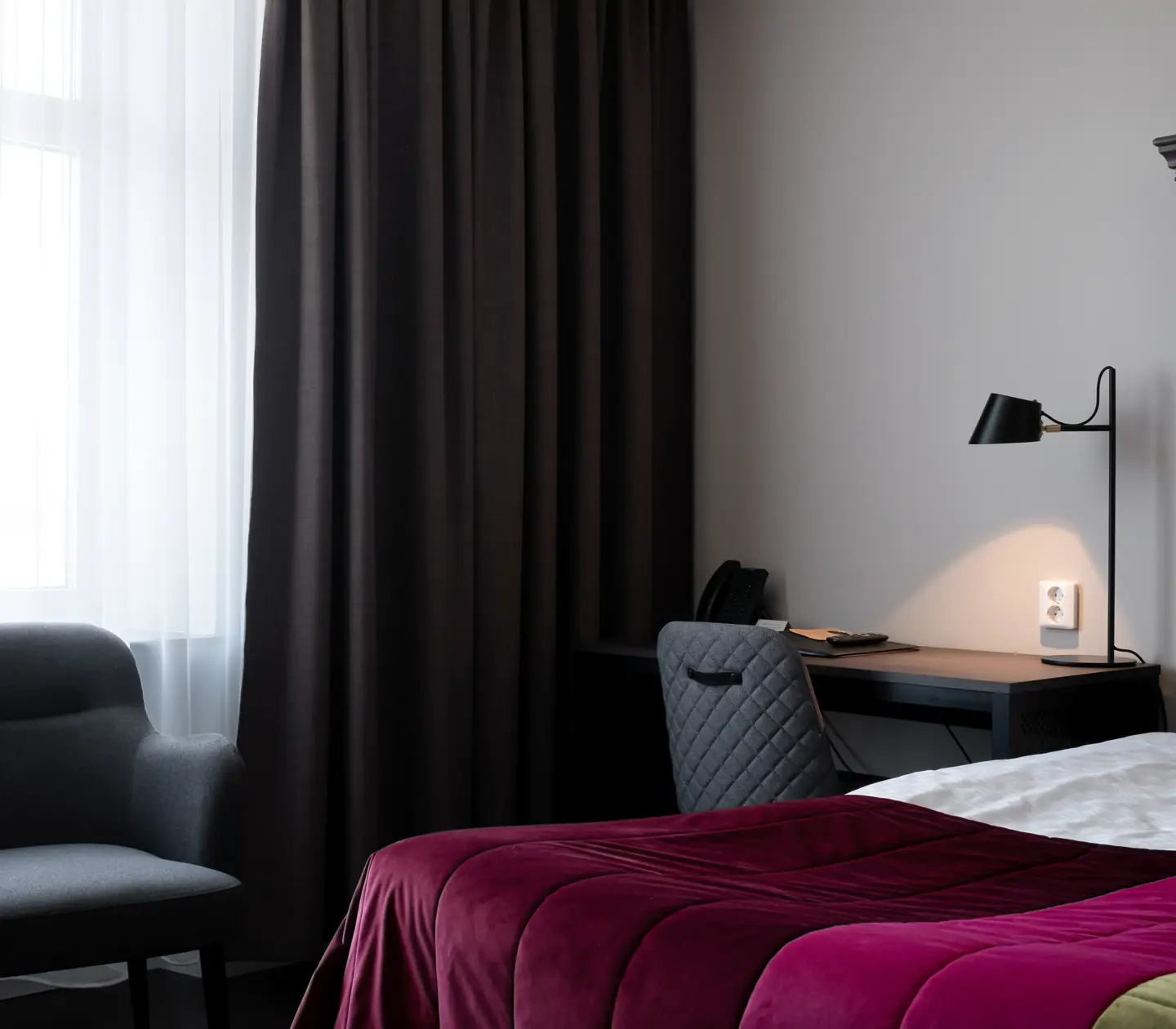 Hotellrum med säng, stor sänggavel i trä och skrivbord