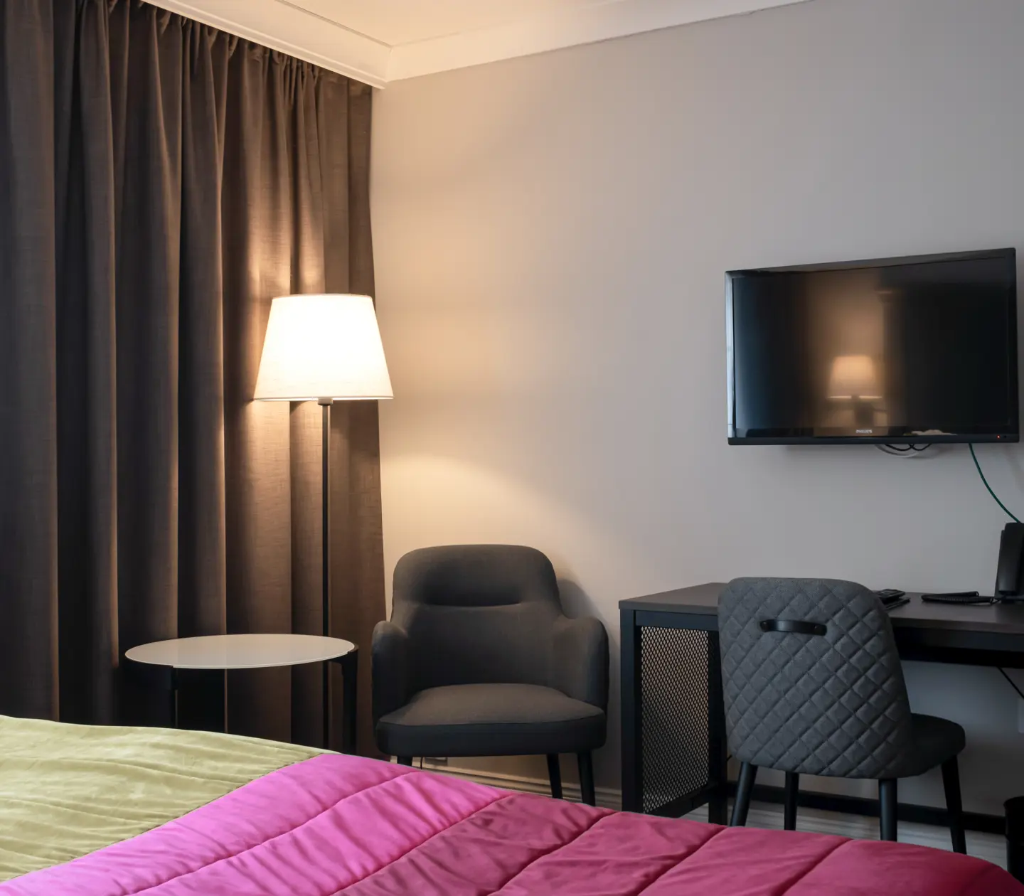 Hotellrum med säng, skrivbord och fåtölj