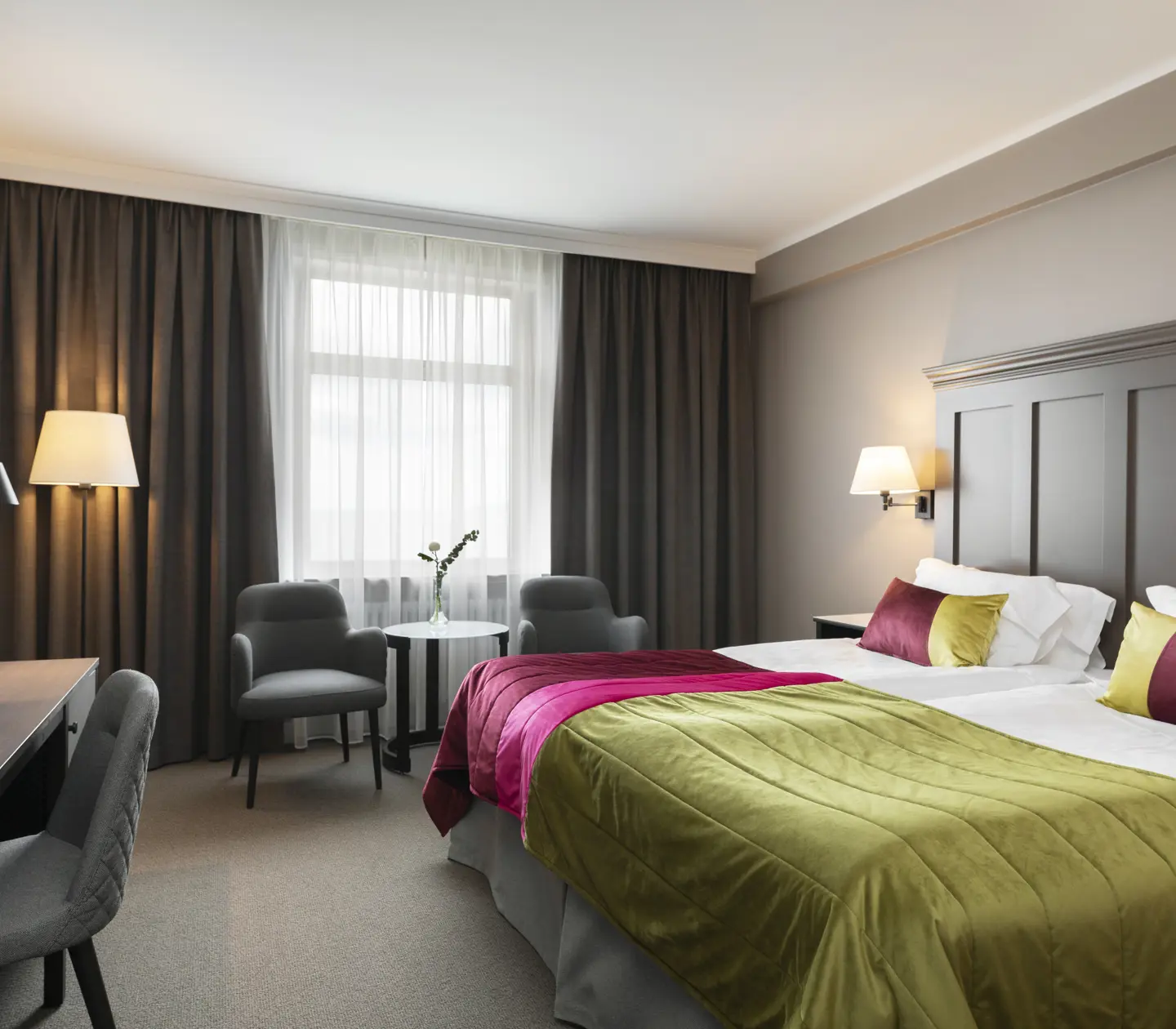Hotellrum med säng, skrivbord och fåtöljer