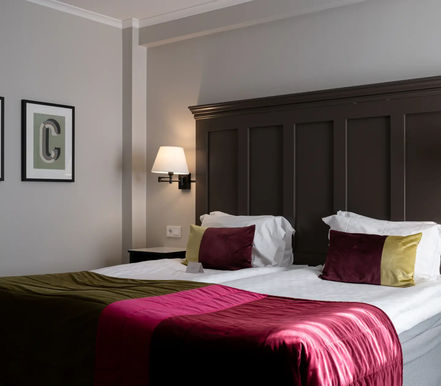 Hotellrum med säng, stor sänggavel i trä och tavlor