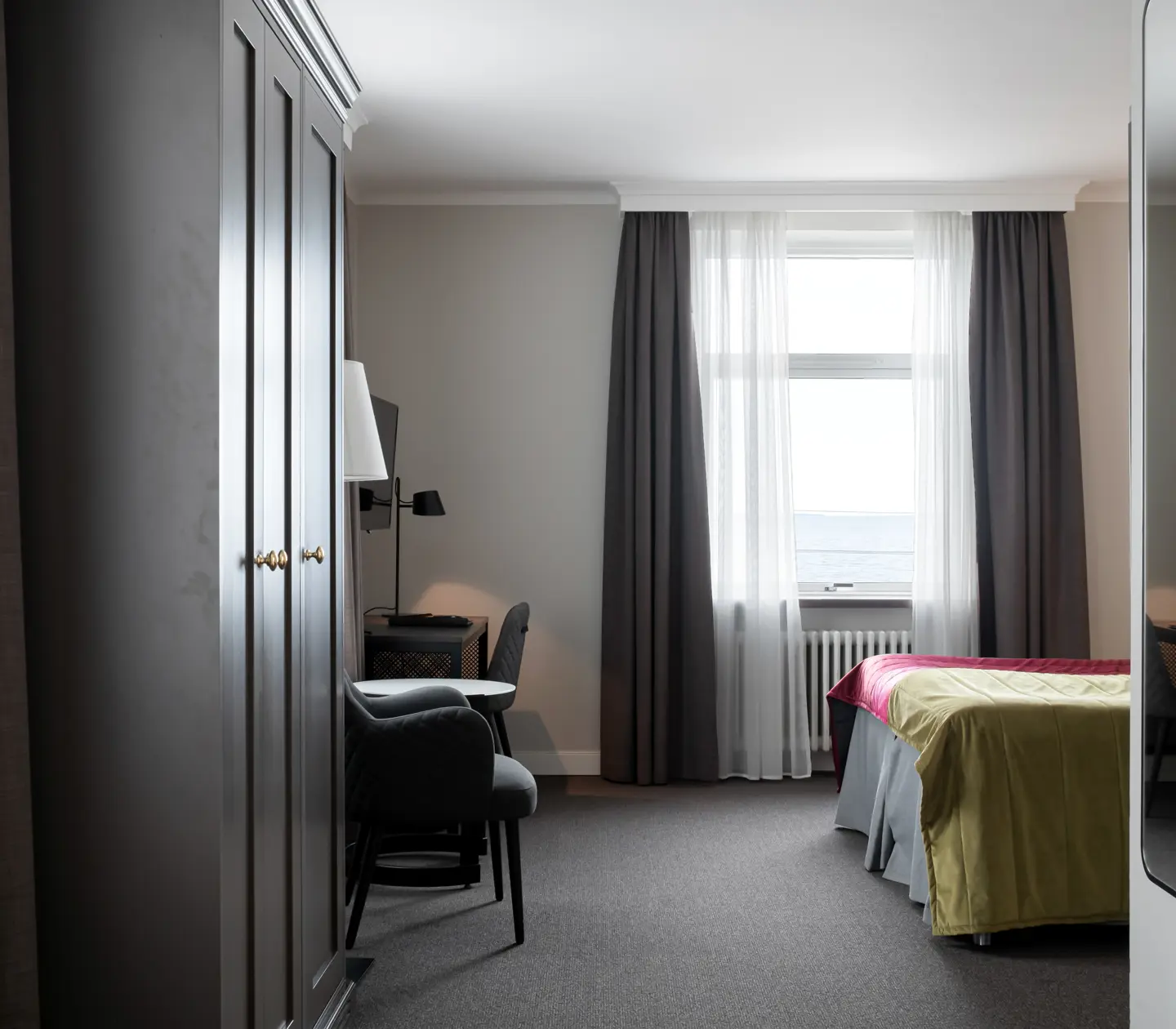 Hotellrum med säng, garderob och havsutsikt