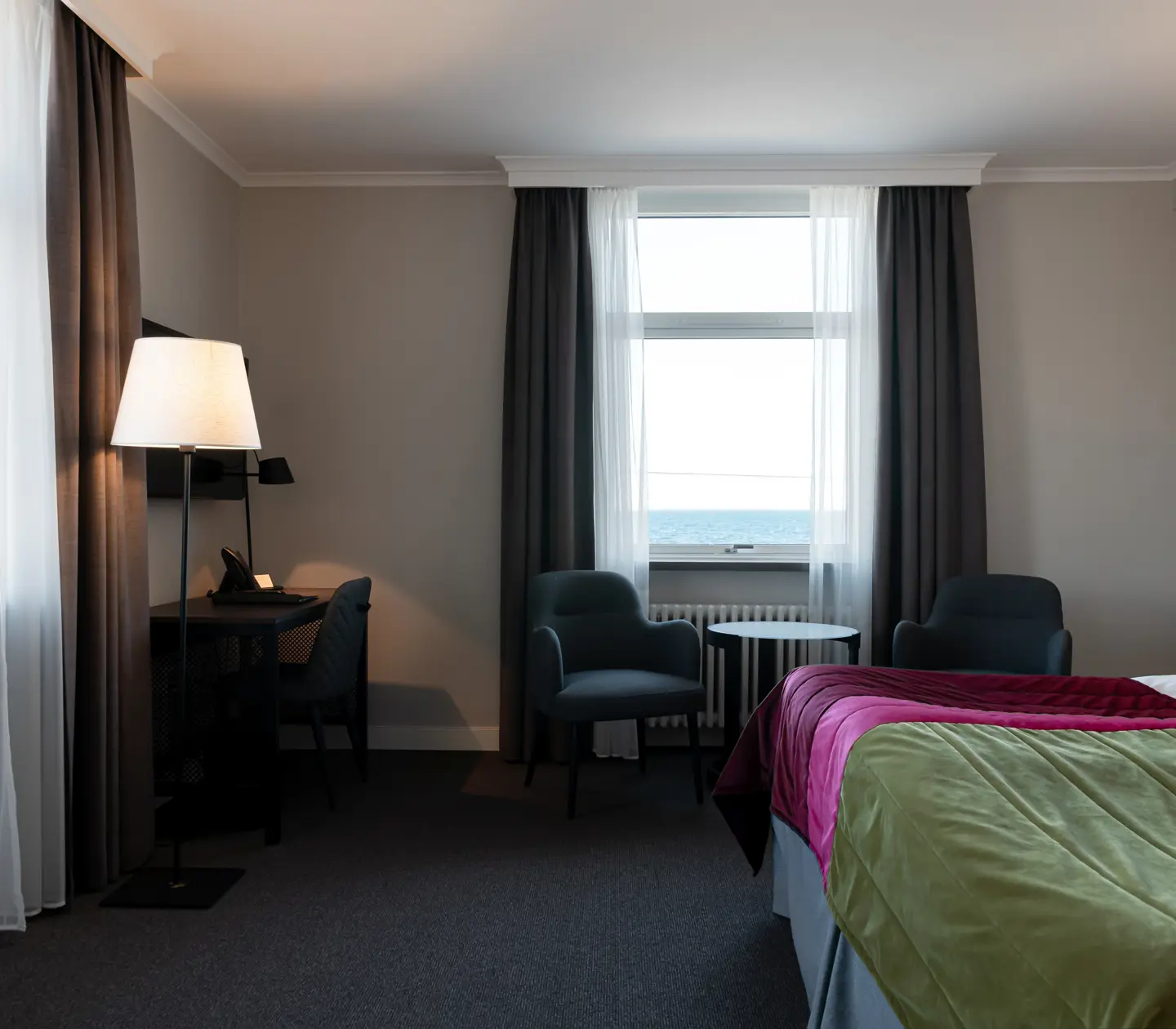 Hotellrum med säng, fåtöljer och skrivbord