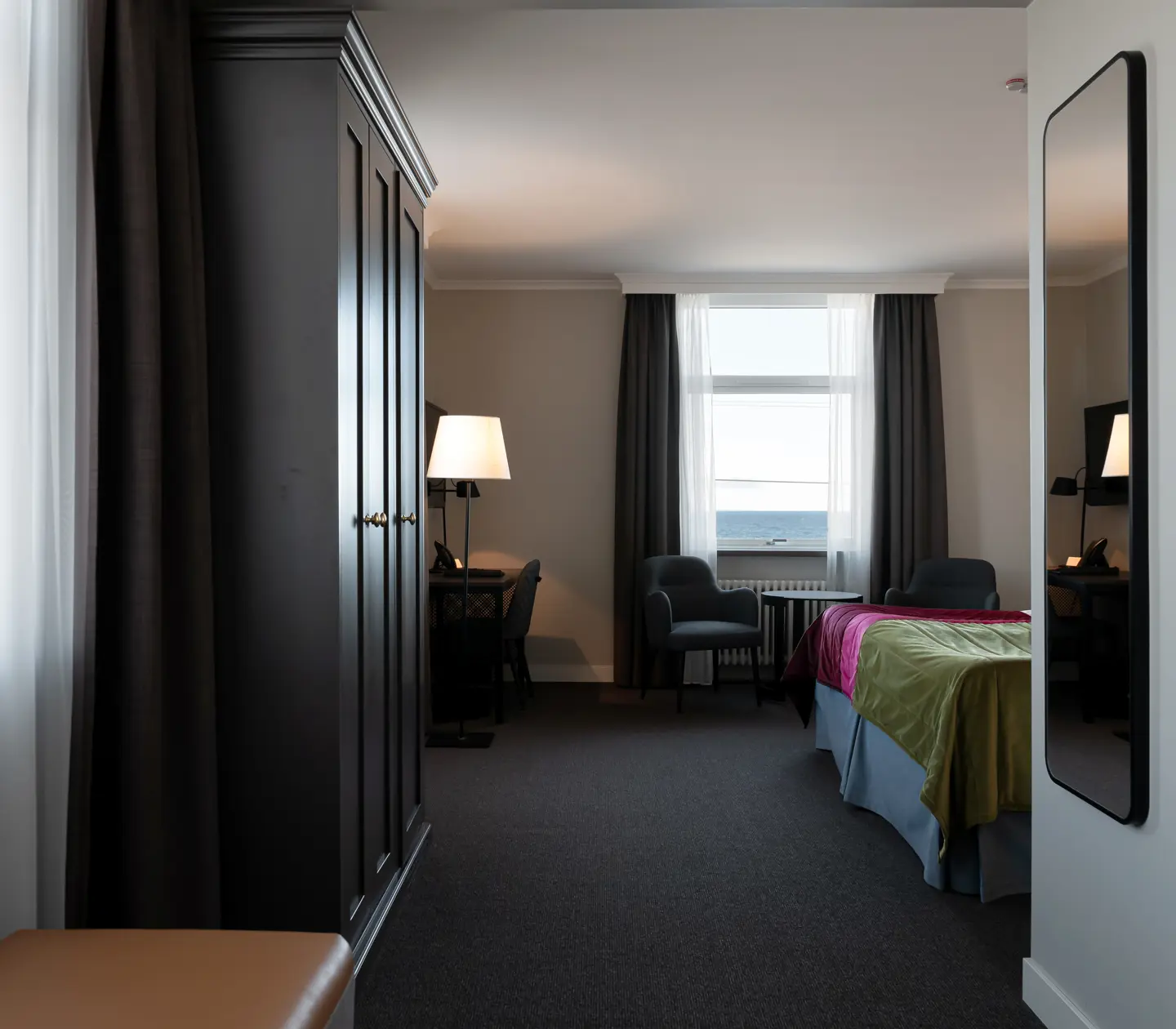 Hotellrum med garderob, skrivbord och havsutsikt